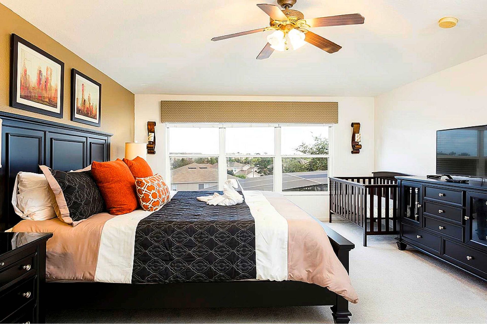 Spacious master suite with a king bed, stylish decor, TV, and a cozy crib for little ones.