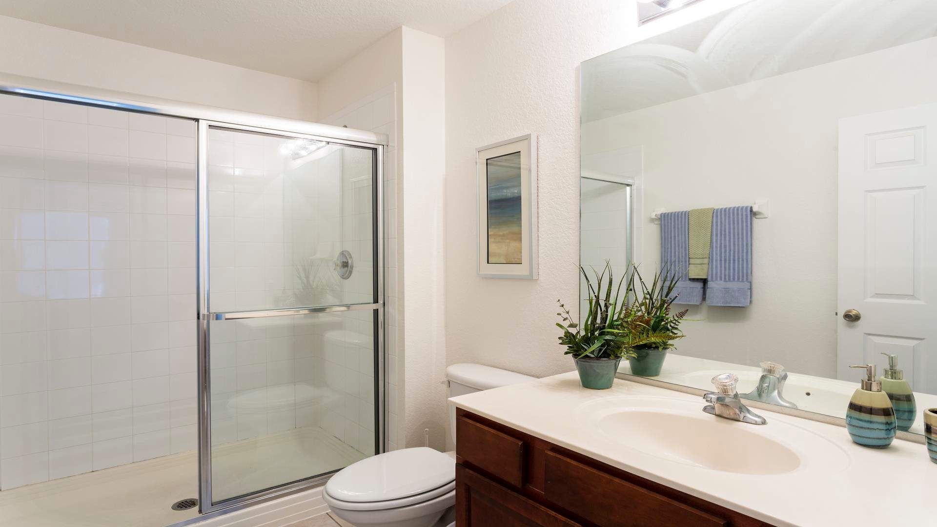 Modern and fresh bathroom with a glass-enclosed shower, stylish decor, and soft linens.
