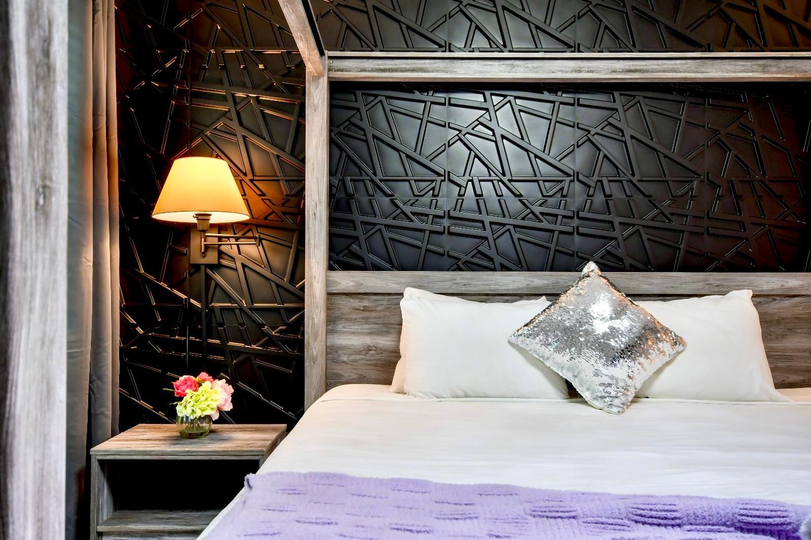 Modern and stylish bedroom with a bold black accent wall, cozy lighting, and luxe decor.