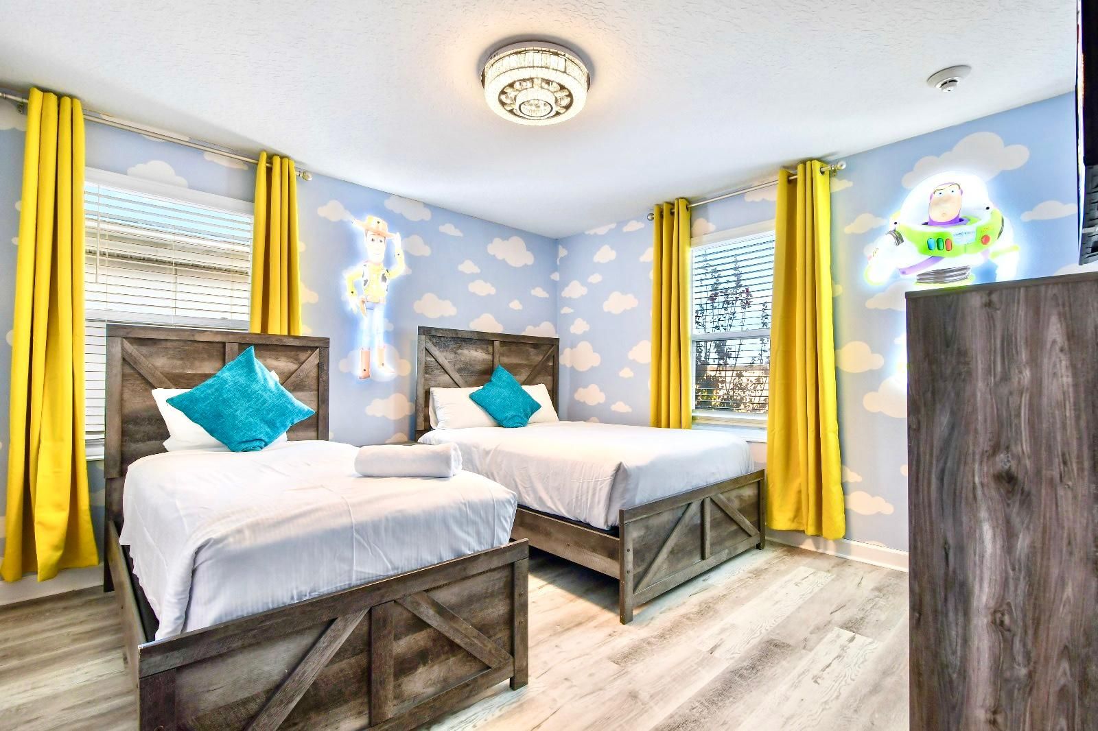 Whimsical Toy Story-themed bedroom with glowing wall art, cloud decor, and cozy beds.