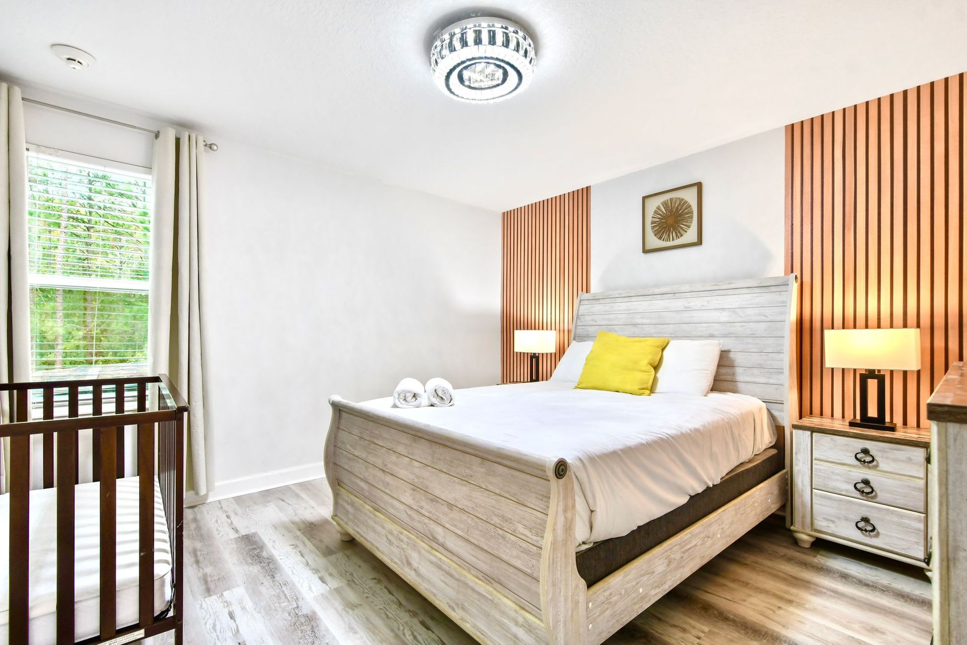 Elegant and cozy bedroom with rustic wood furniture, warm lighting, and a crib for comfort.