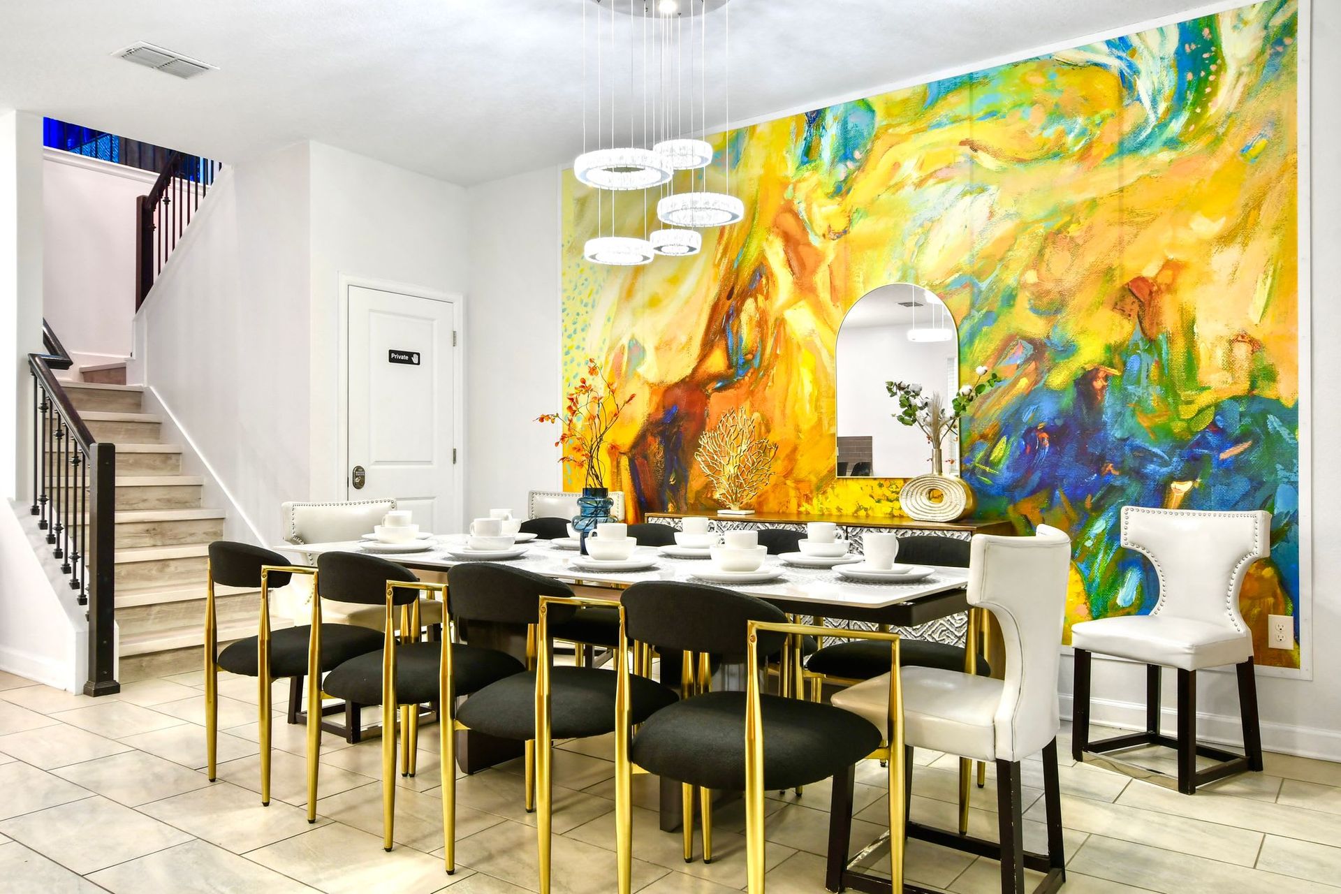 Elegant dining area with bold artistic wall, modern gold accents, and chic seating.