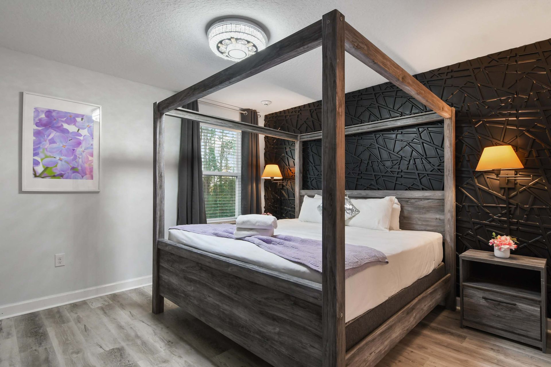Sophisticated bedroom with a modern canopy bed, bold black accent wall, and warm lighting.