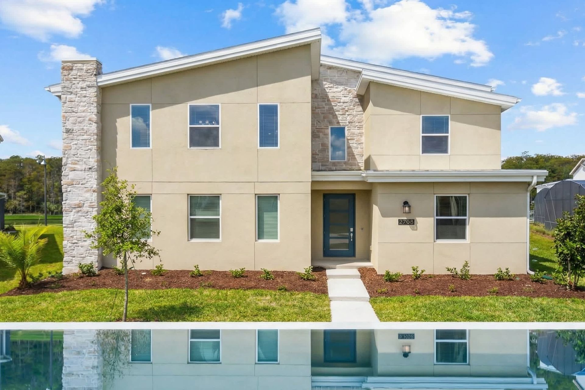 Contemporary home design featuring a modern aesthetic with a touch of brick for a timeless charm, complemented by lush greenery.