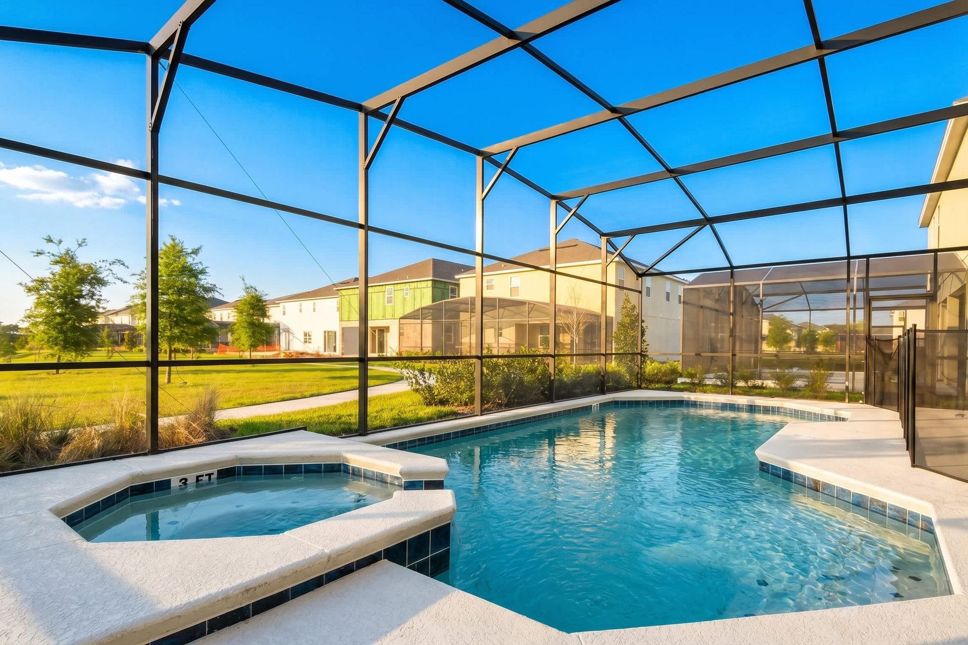 Screened-in pool with spa overlooking a serene lake and lush greenery.