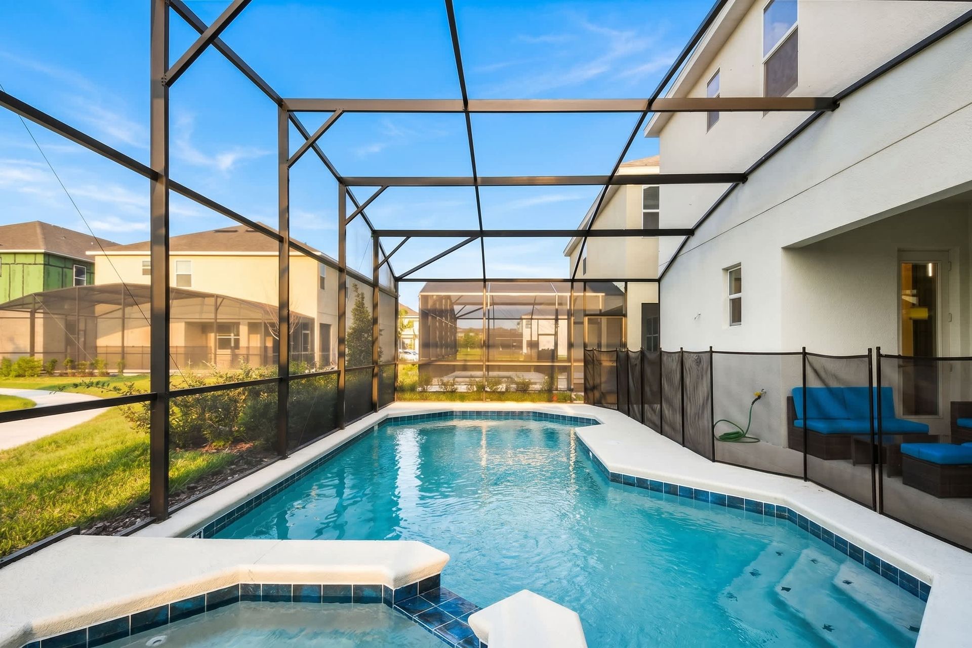 Screened-in pool with spa overlooking a serene lake and lush greenery.