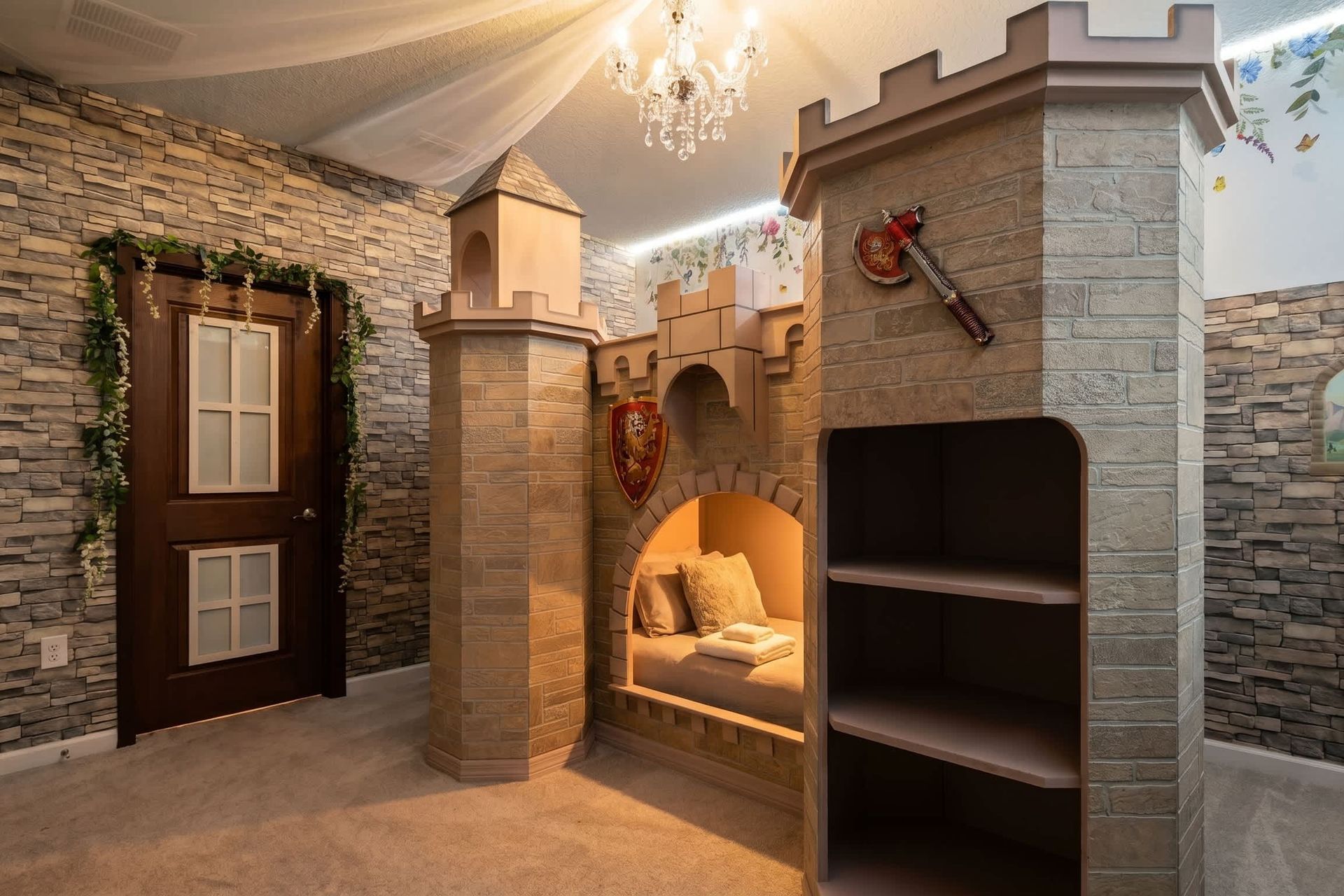 Castle-themed bedroom with stone walls, cozy nook, and chandelier—fairytale escape
