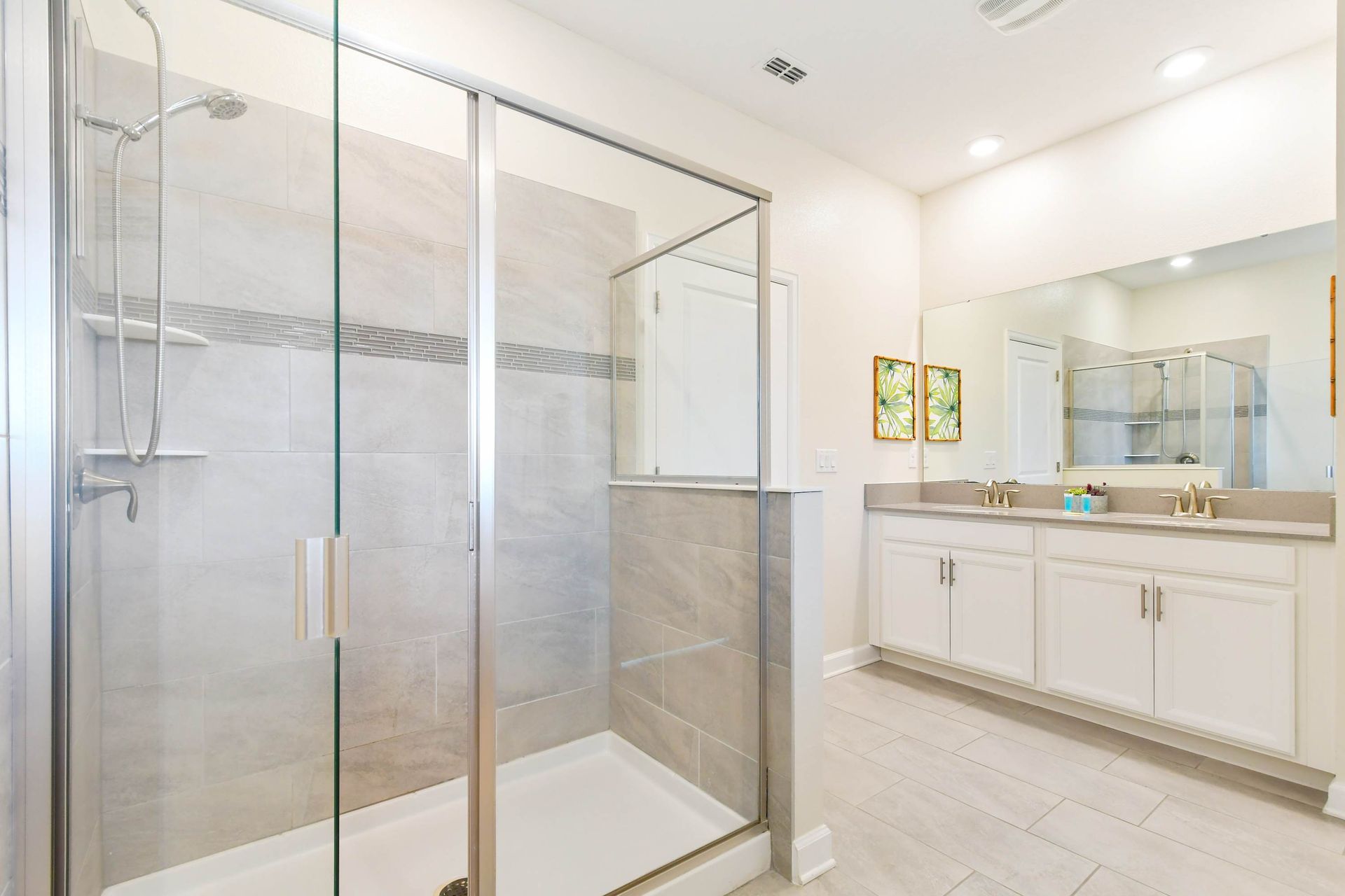 Spacious modern bathroom with a glass walk-in shower, dual vanity, and elegant design