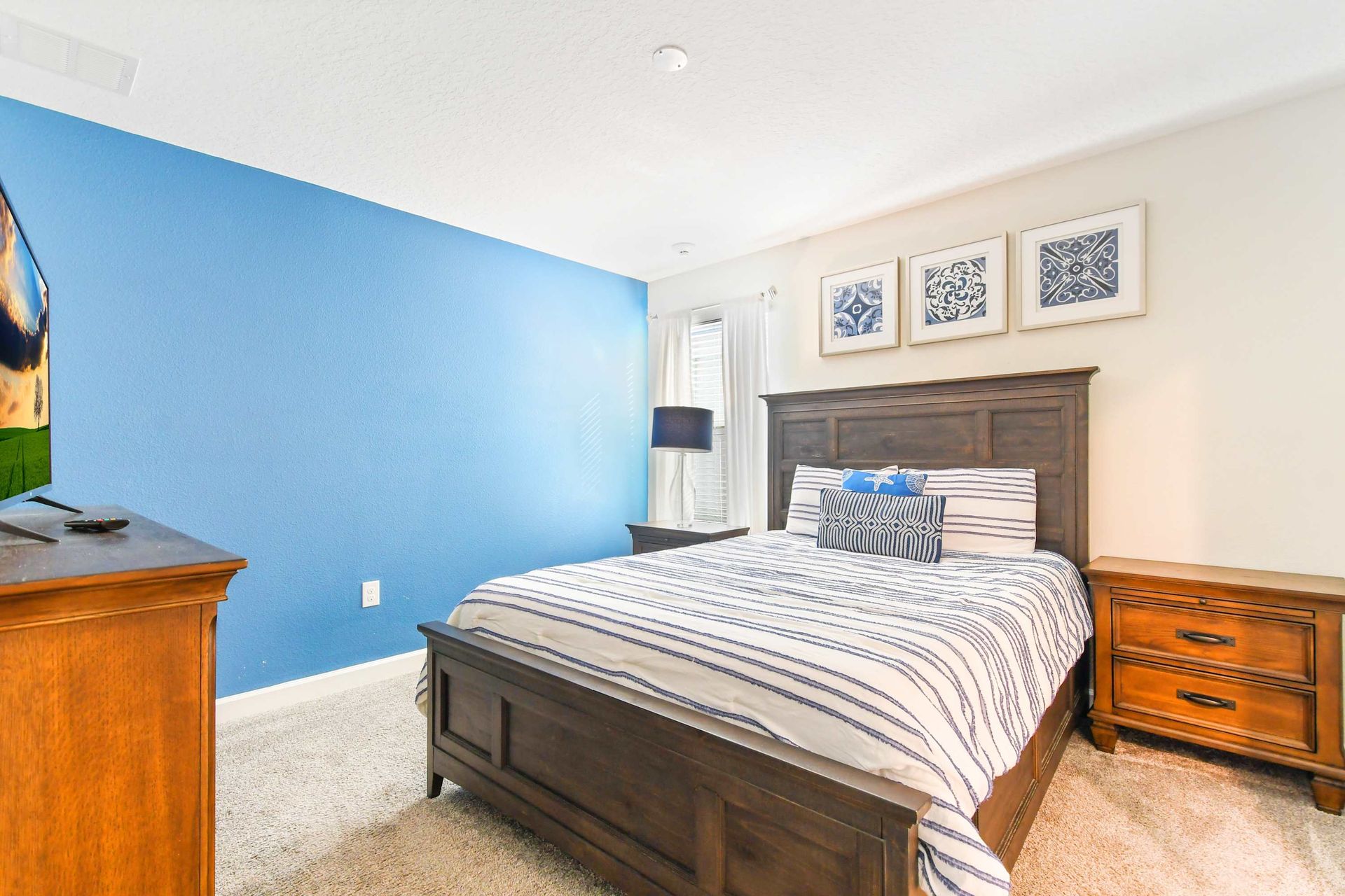 Stylish coastal bedroom with rich wood furnishings, blue accents, and cozy ambiance