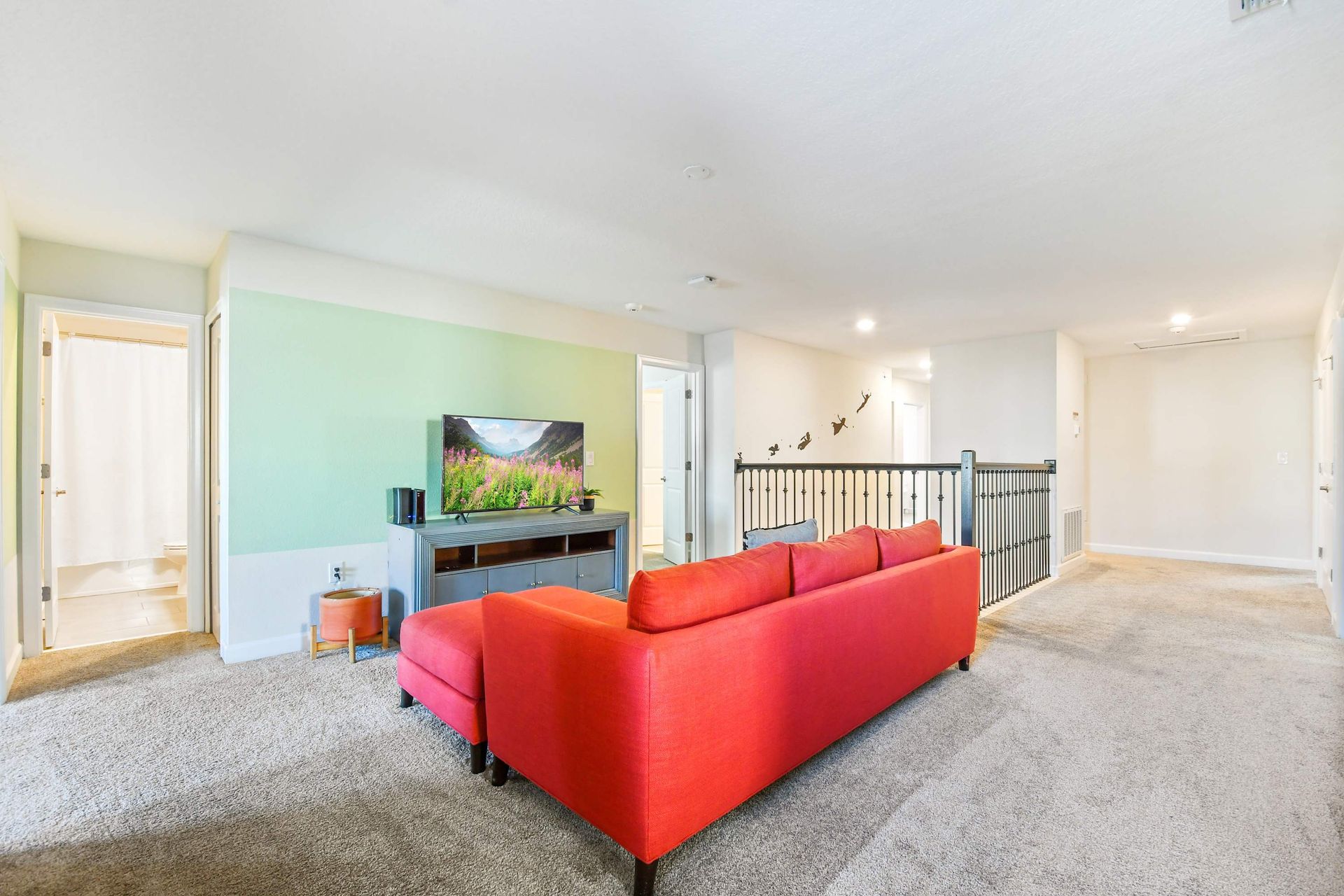 Cozy upstairs loft with a bold sectional, entertainment center, and relaxing vibe