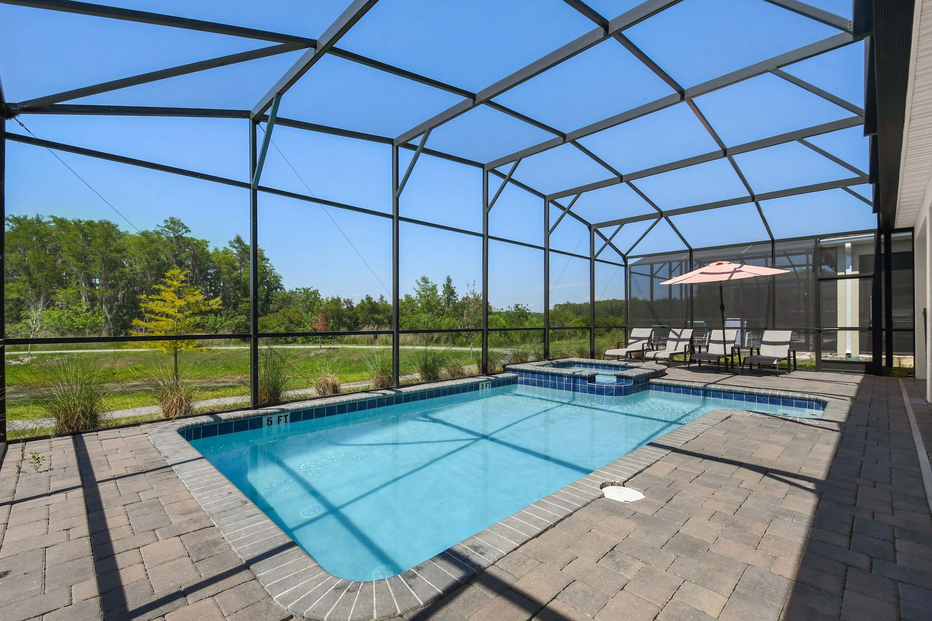 Screened-in private pool with a spa, lounge chairs, and a shaded seating area