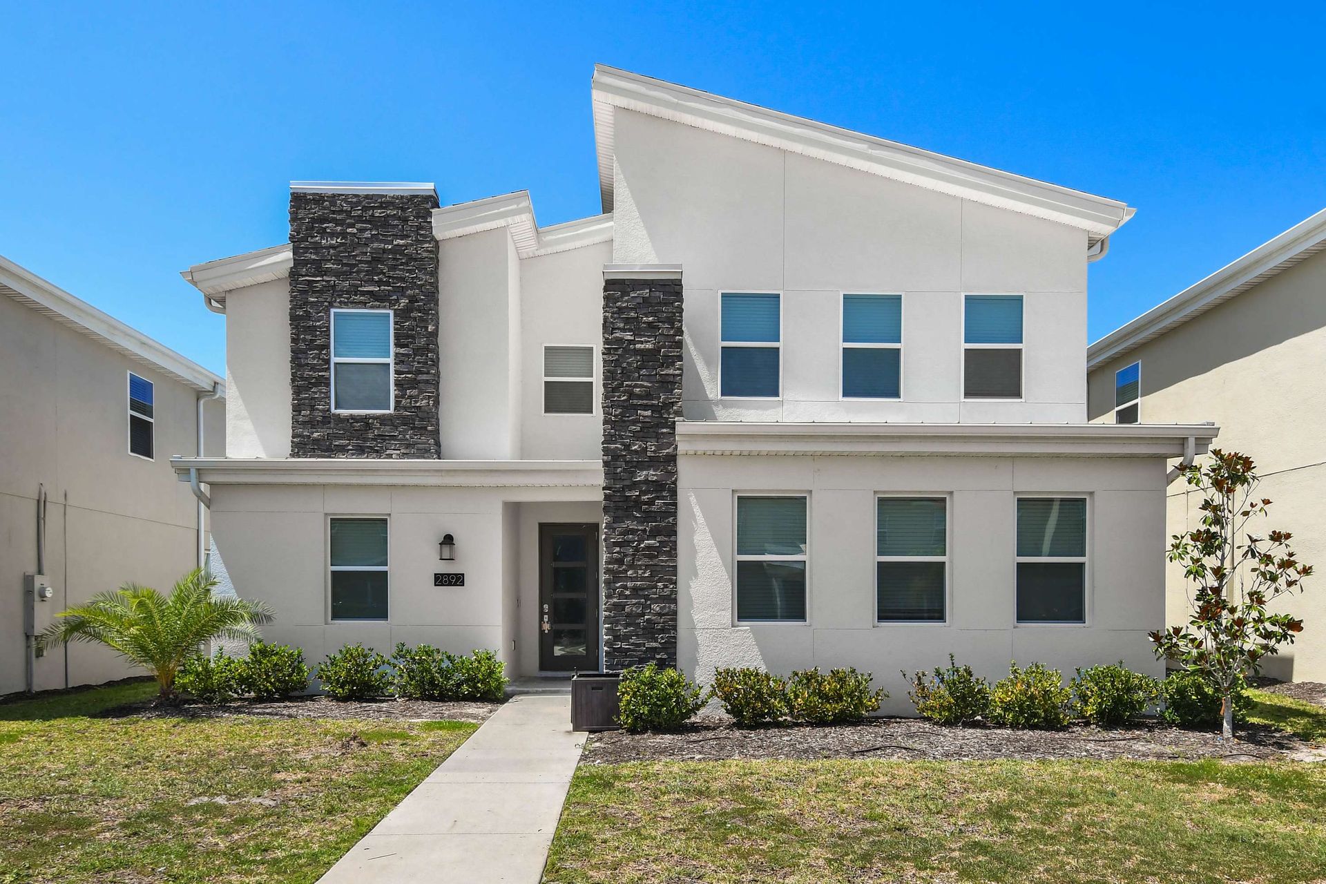 Modern and spacious home with sleek architecture, stone accents, and lush landscaping