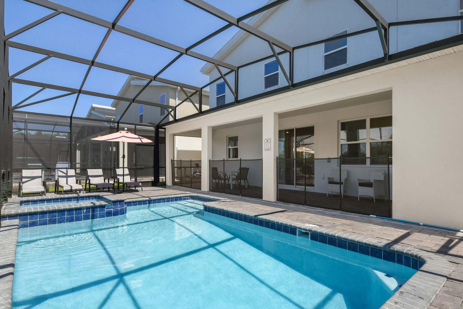 Screened-in private pool with a spa, lounge chairs, and a shaded seating area
