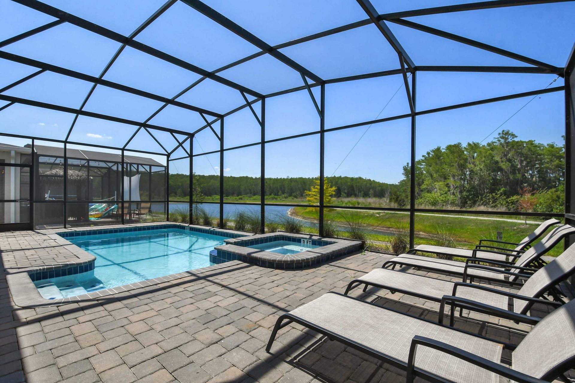Screened-in pool and spa with serene lake views, lounge chairs, and total privacy.