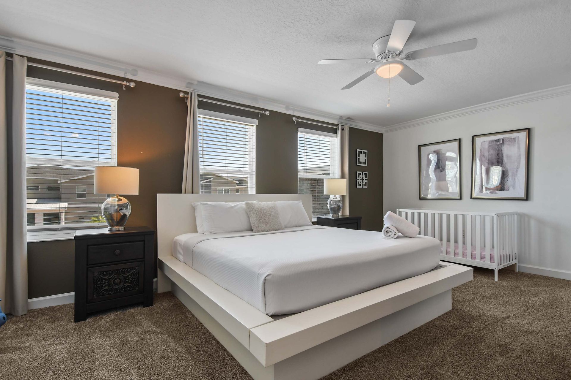 Spacious master suite with a modern king bed, cozy lighting, and a crib for comfort