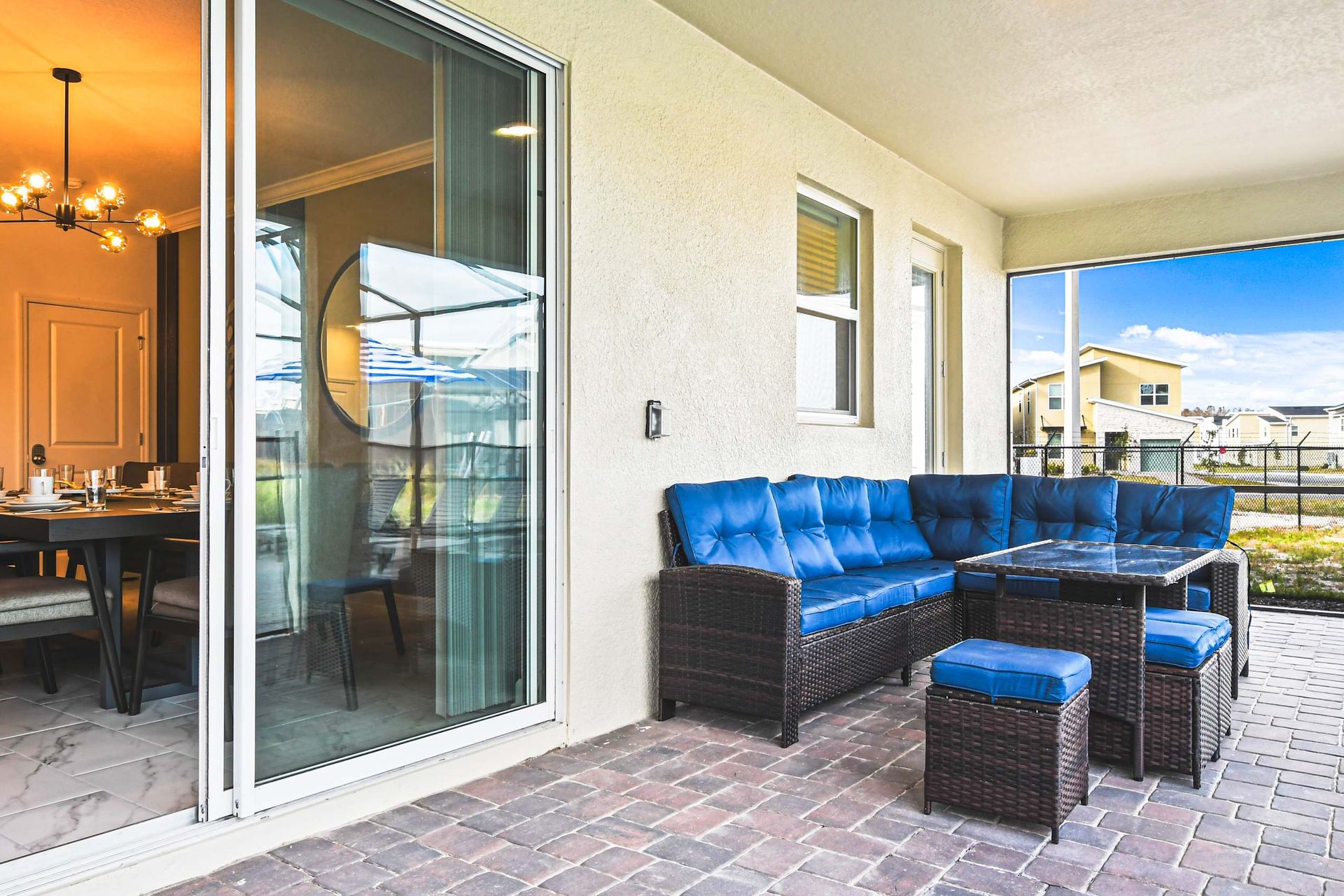 Relaxing screened-in patio with cozy seating, outdoor dining, and neighborhood views.