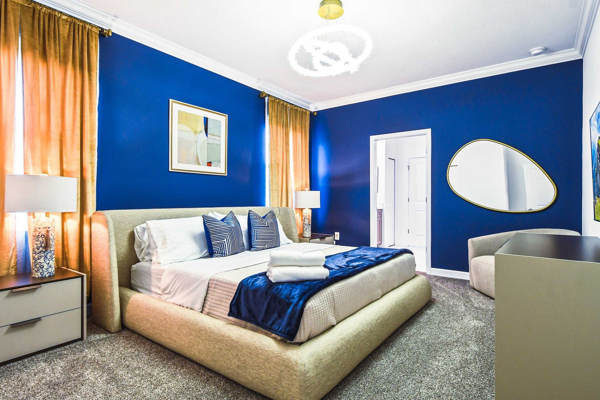 Sophisticated bedroom with bold blue walls, plush bedding, and elegant gold accents.