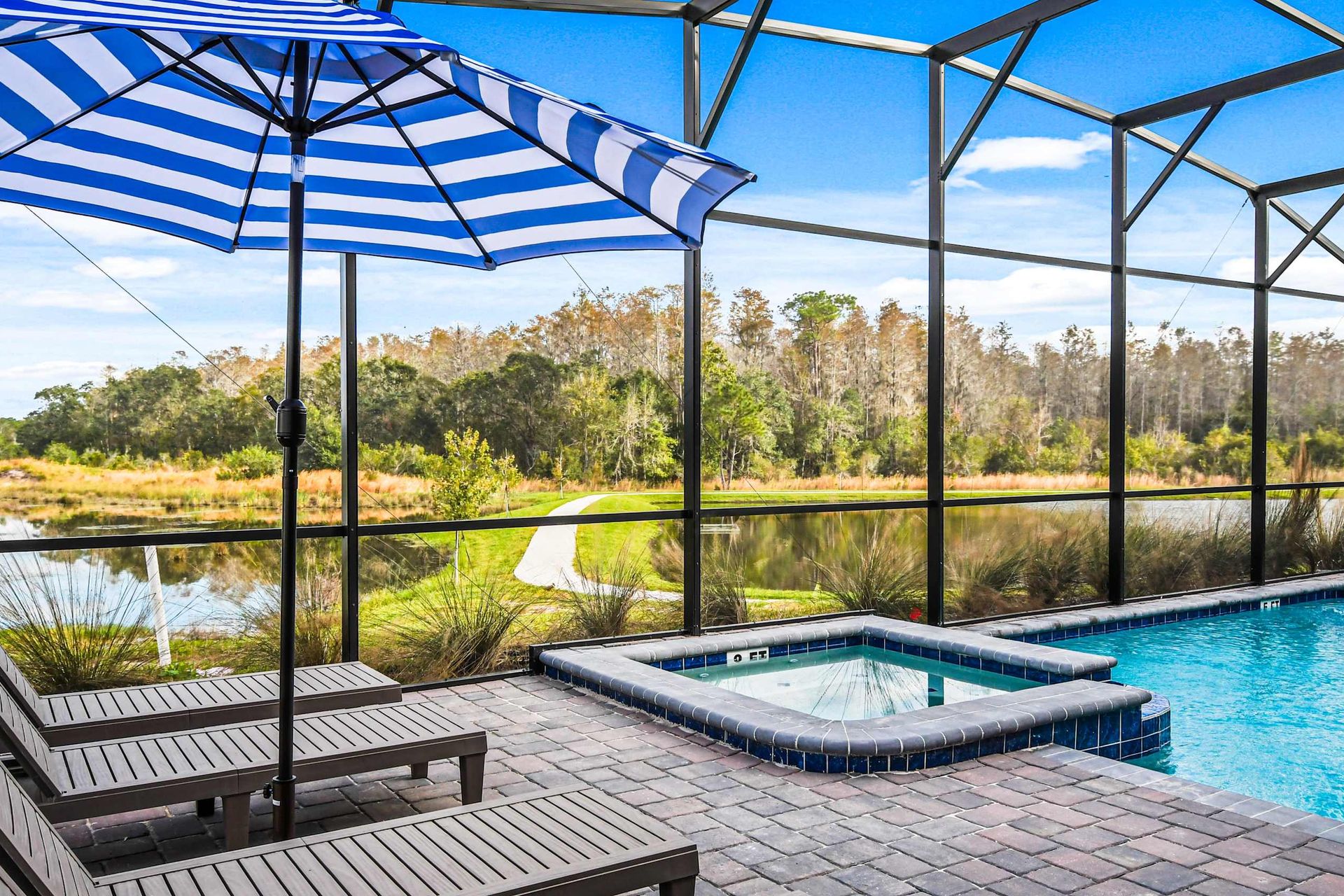 Screened-in pool and spa with stunning lake views, lounge chairs, and shade.