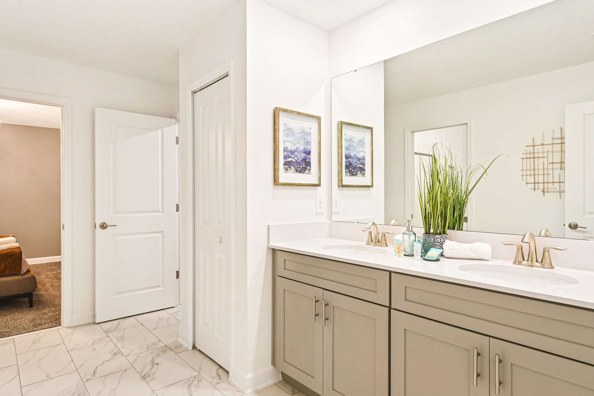 Bright and modern bathroom with a double vanity, elegant decor, and gold accents.