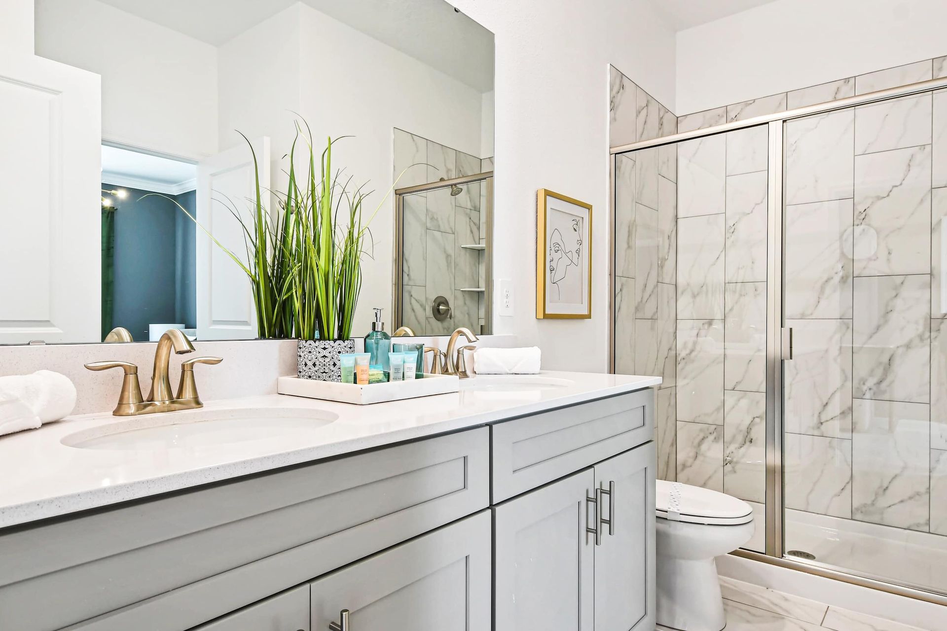 Modern bathroom with a marble shower, double vanity, and elegant gold fixtures.