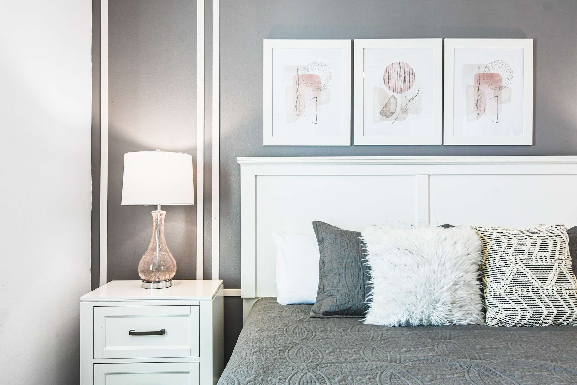Chic bedroom corner with cozy king bed, modern nightstand, soft lighting and decor
