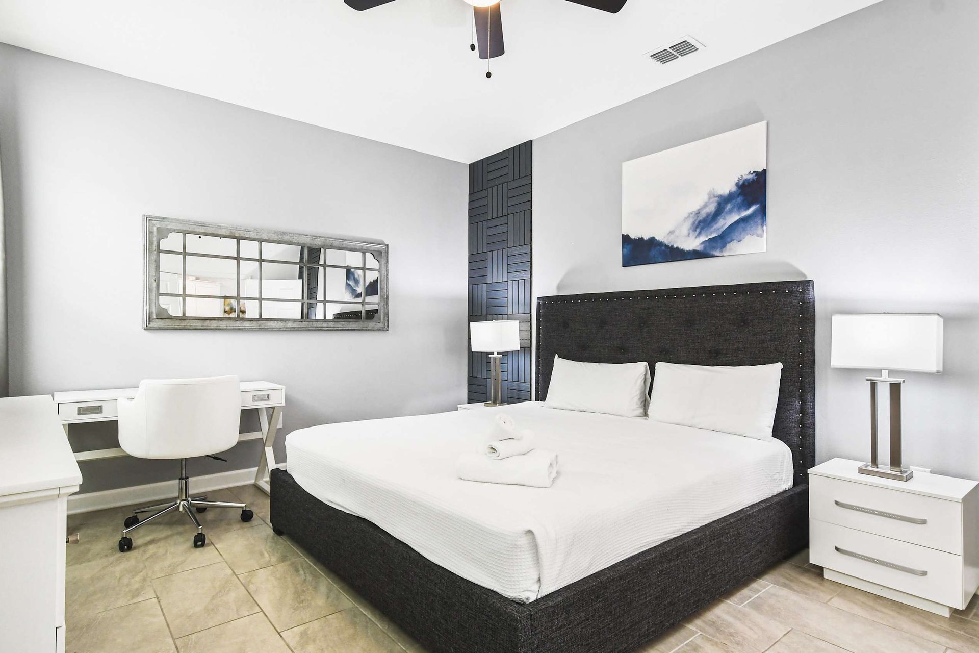 Modern bedroom with king bed, stylish accent wall, work desk, TV and serene decor
