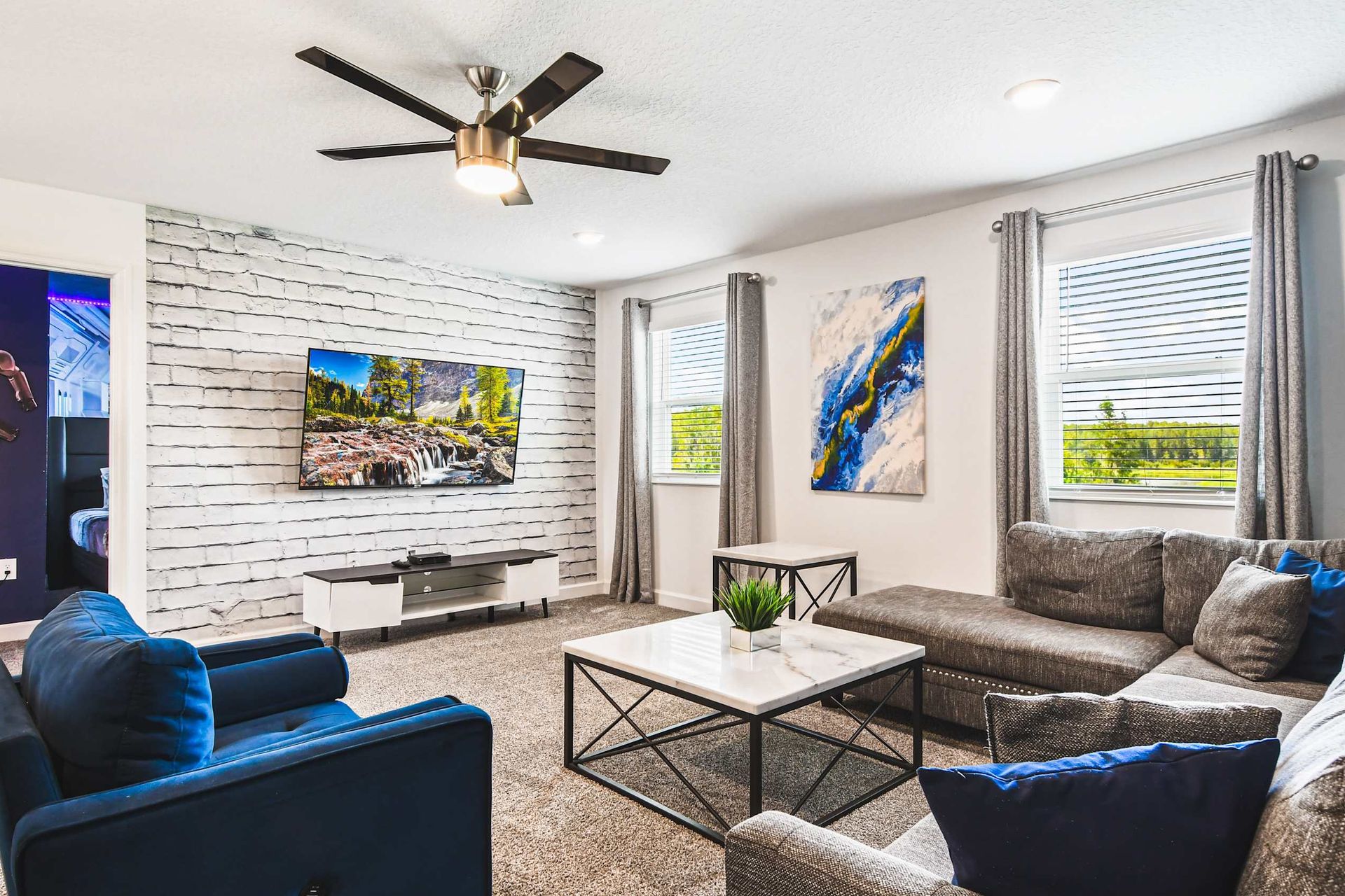 Cozy upstairs lounge with big sectional, smart TV, modern decor and fun movie theme
