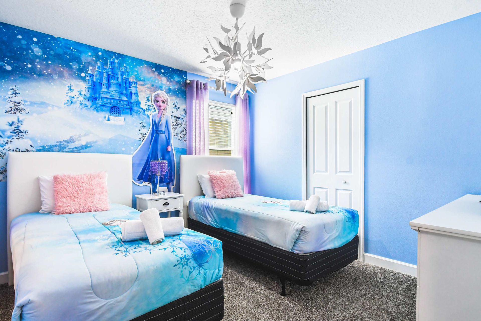Frozen-themed kids’ room with twin beds, snowy mural, fluffy pillows and magical vibe
