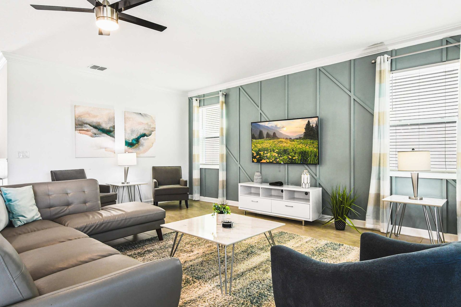 Chic open living room with modern sectional, smart TV, stylish walls and bright light
