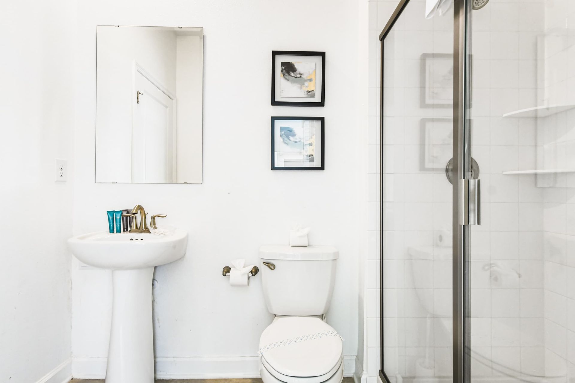 Bright clean bathroom with walk-in shower, pedestal sink, fresh towels and modern decor
