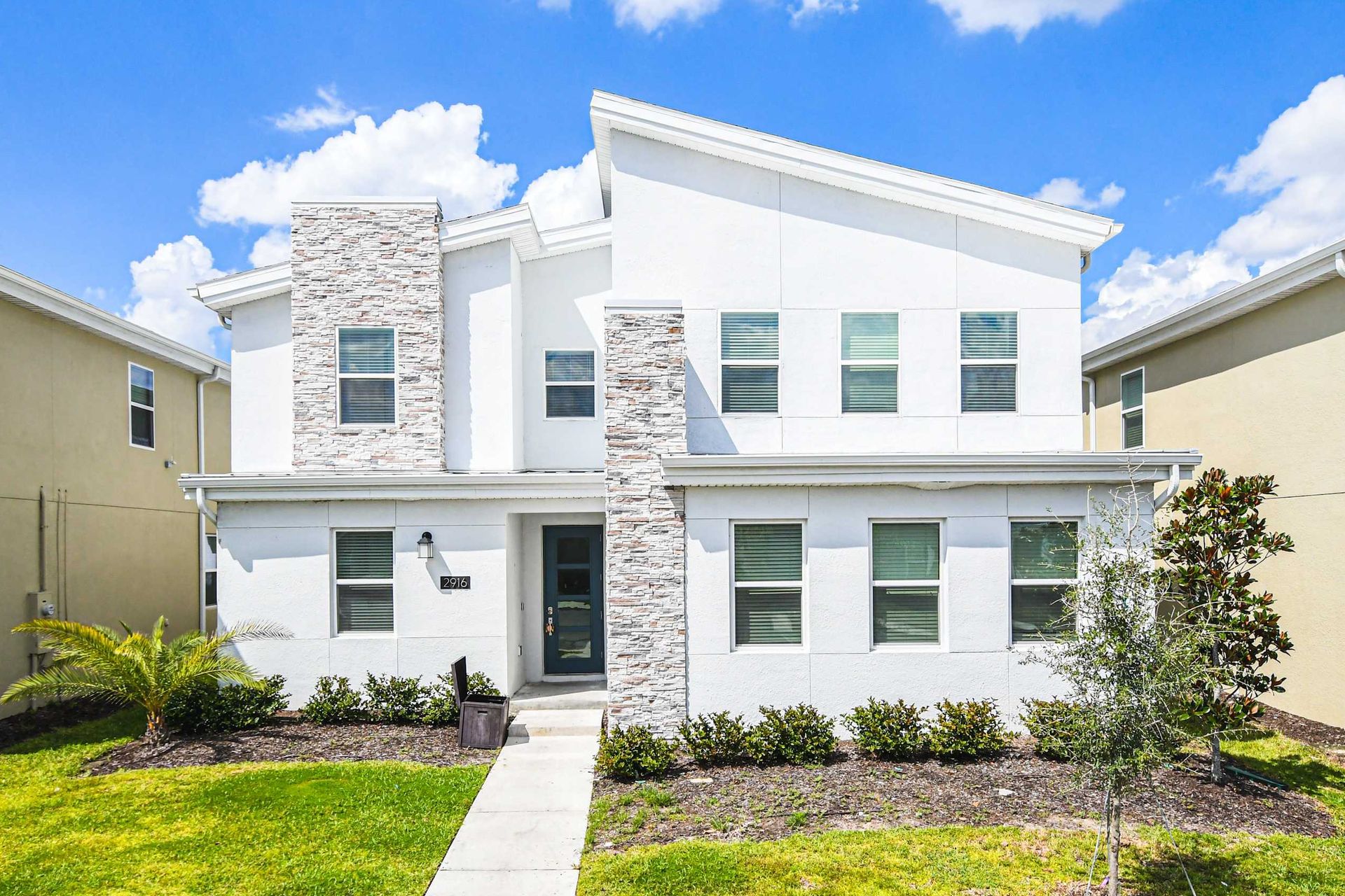 Modern spacious villa with bright exterior, stylish stone accents and welcoming entry
