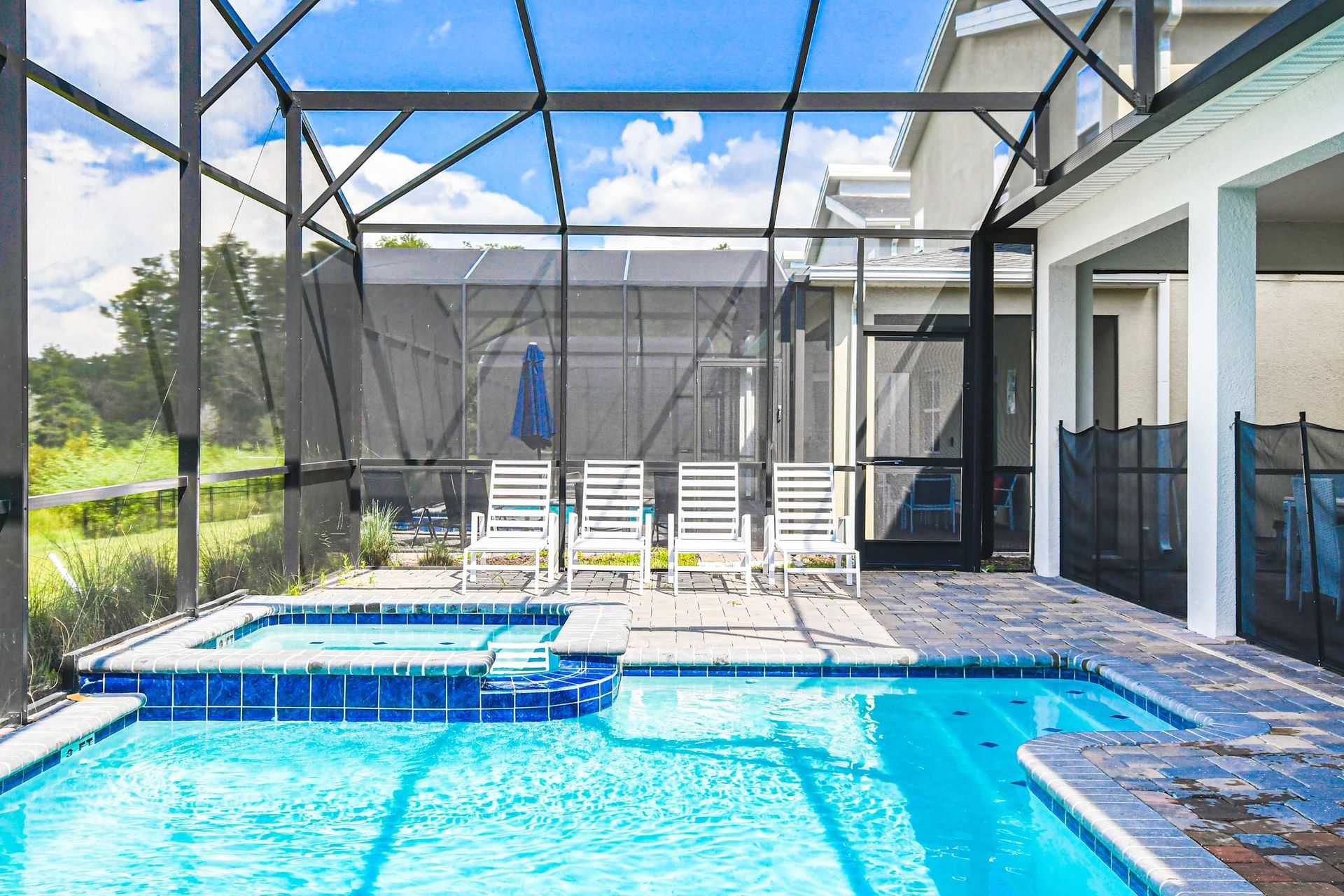 Private screened pool with spa, sun loungers, patio dining and relaxing green view
