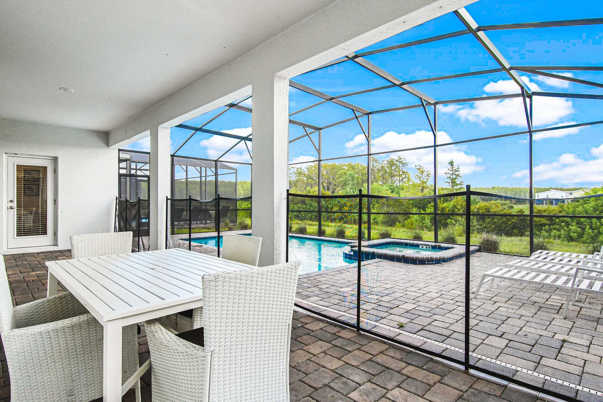 Covered patio dining by private screened pool and spa, with peaceful green views
