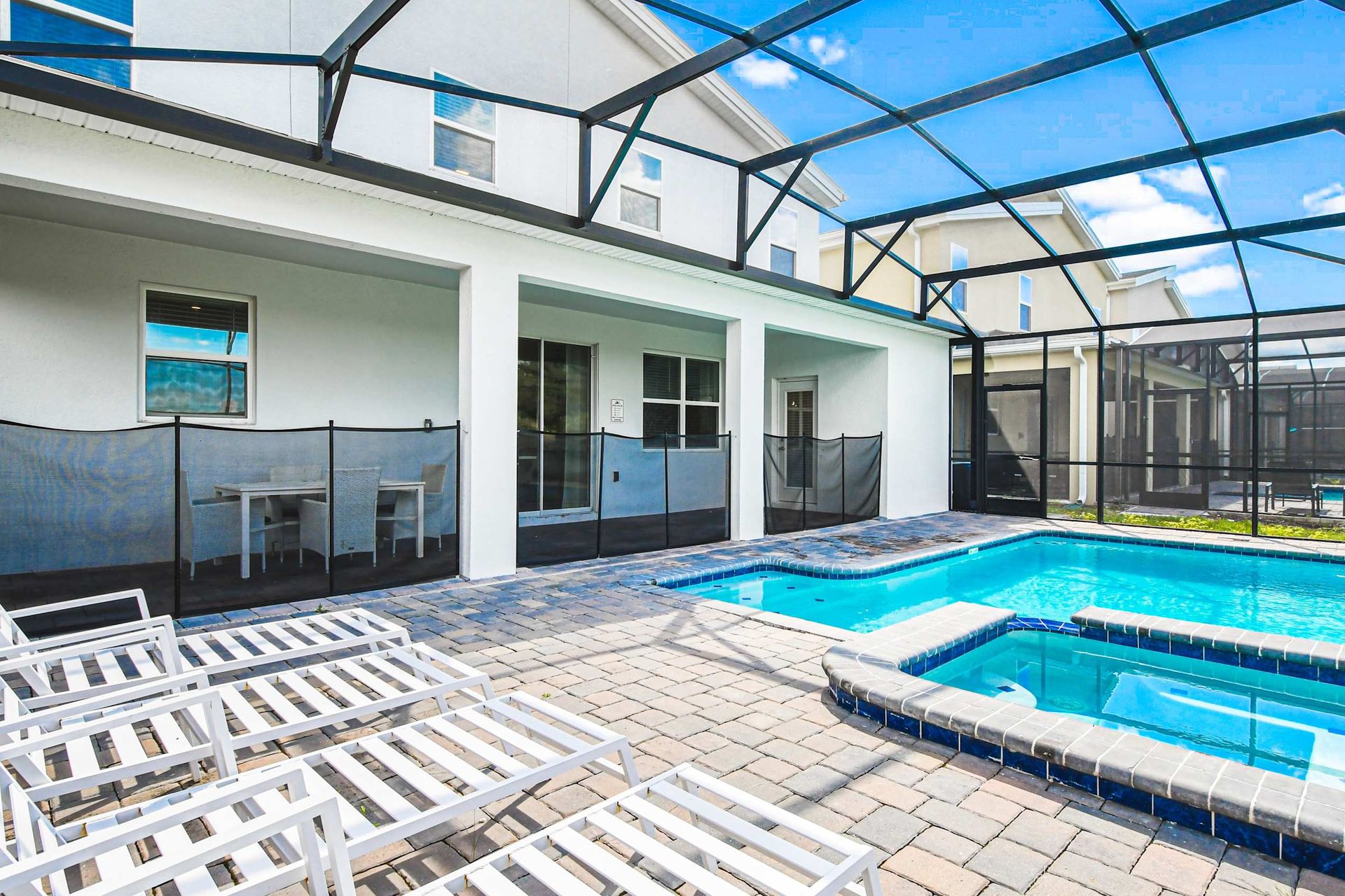 Sunny screened pool and spa with lounge chairs, covered patio dining and relaxing vibes
