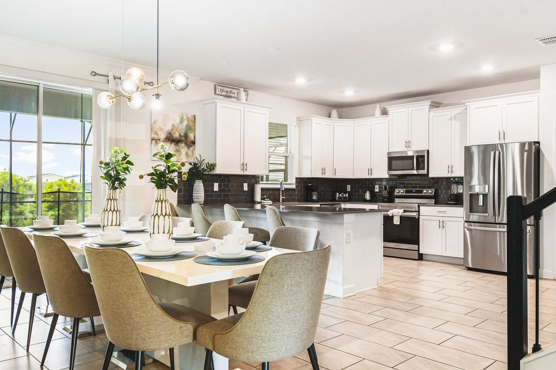 Elegant open kitchen and dining area with modern appliances, bright decor and pool view
