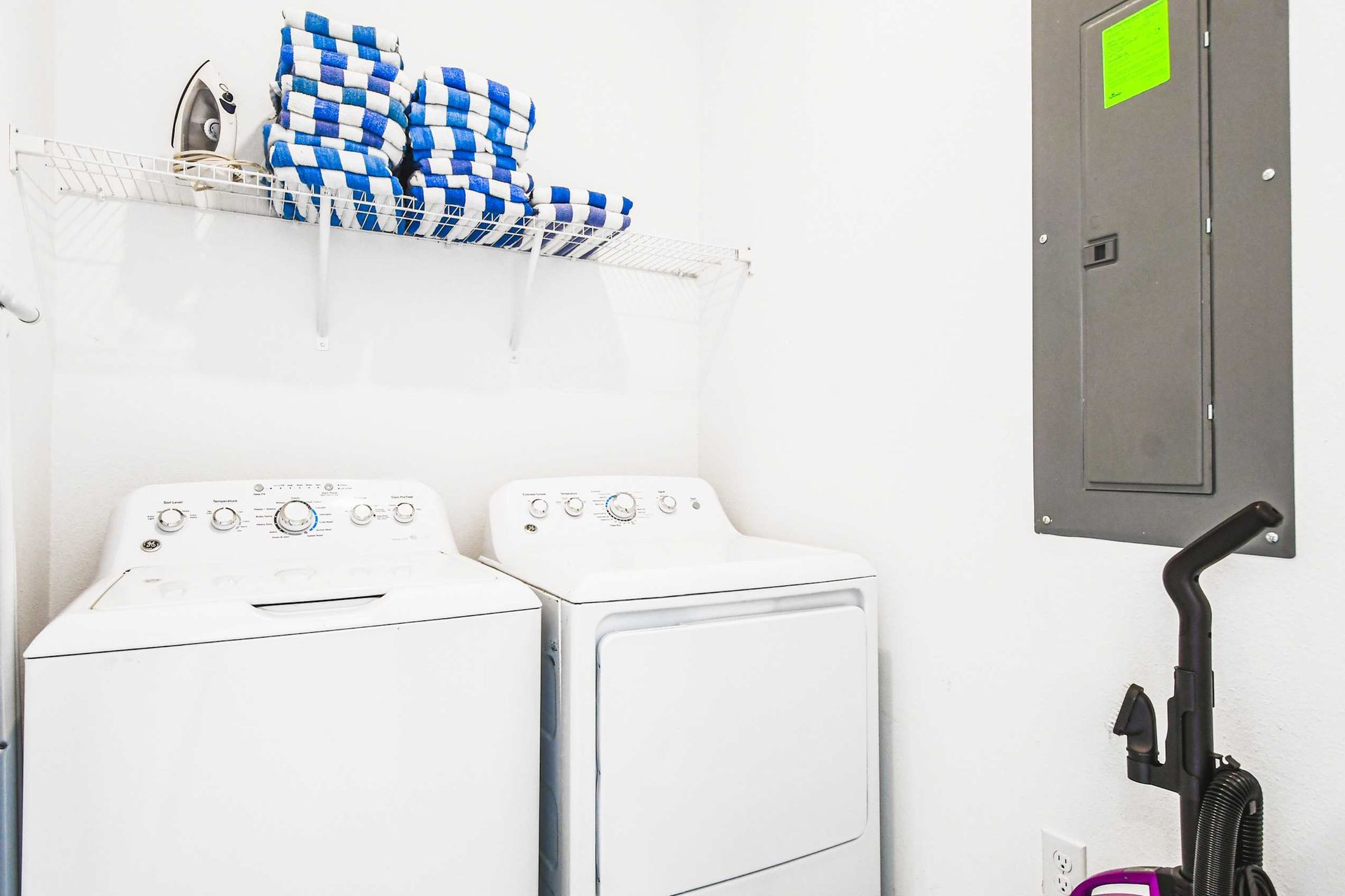 Convenient laundry room with washer, dryer, fresh towels, iron, ironing board and vacuum
