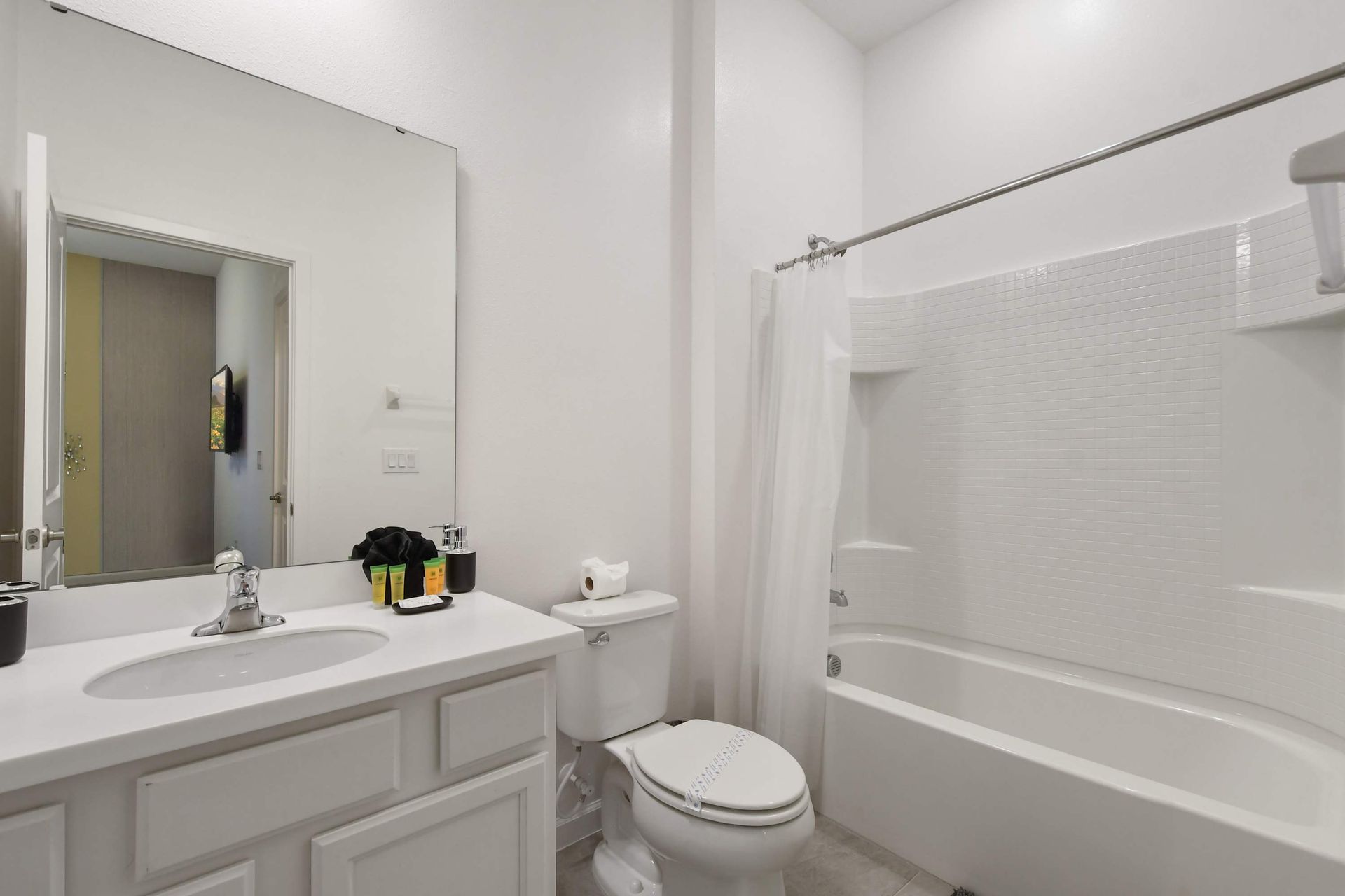 Bright and clean bathroom with a large mirror and a full shower-tub combo.