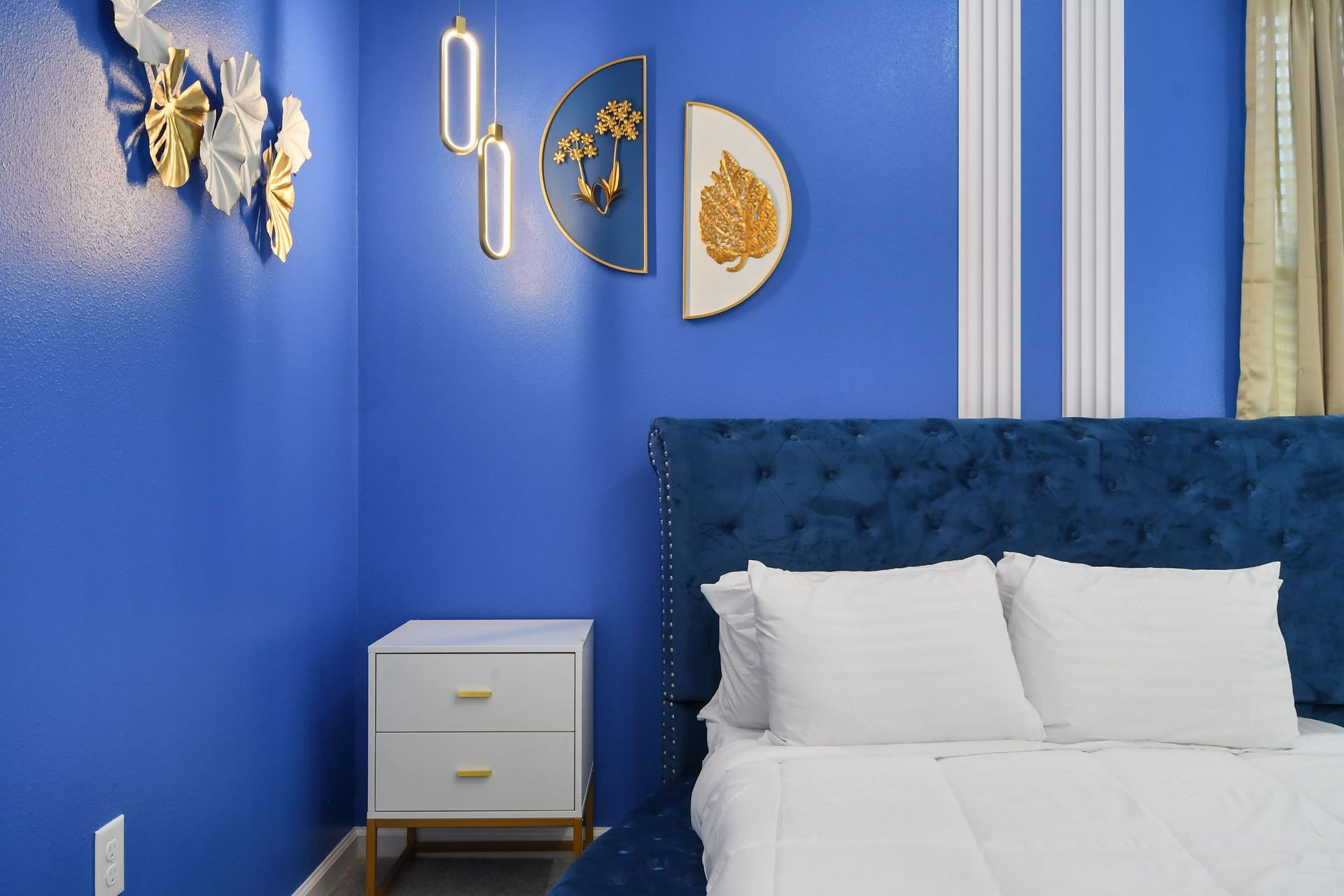 Bold bedroom with royal blue walls, gold accents, and elegant tufted headboard.