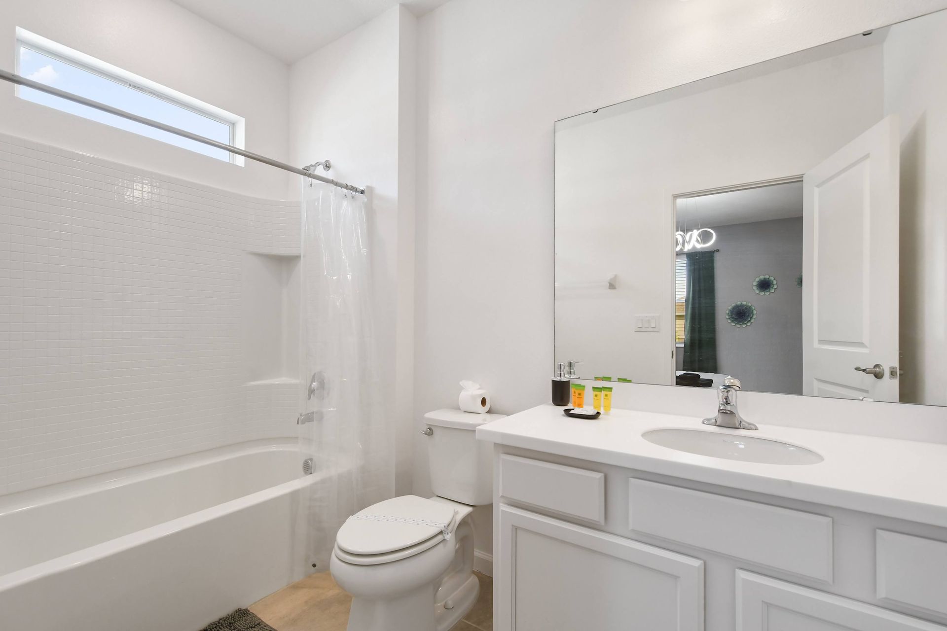 Bright and clean bathroom with a large mirror and a full shower-tub combo.