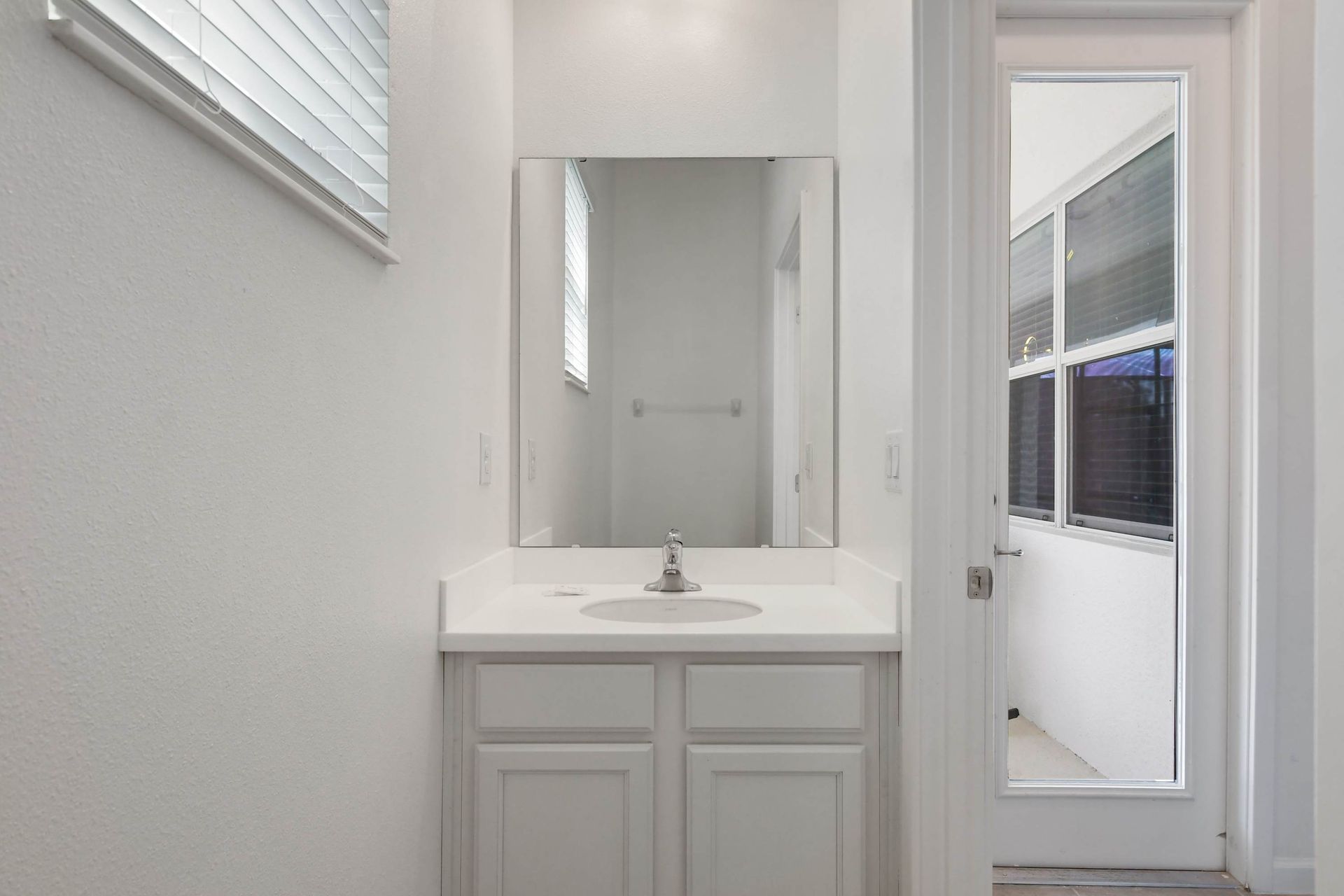 Bright bathroom with a large mirror, clean white cabinetry, and a spacious shower.