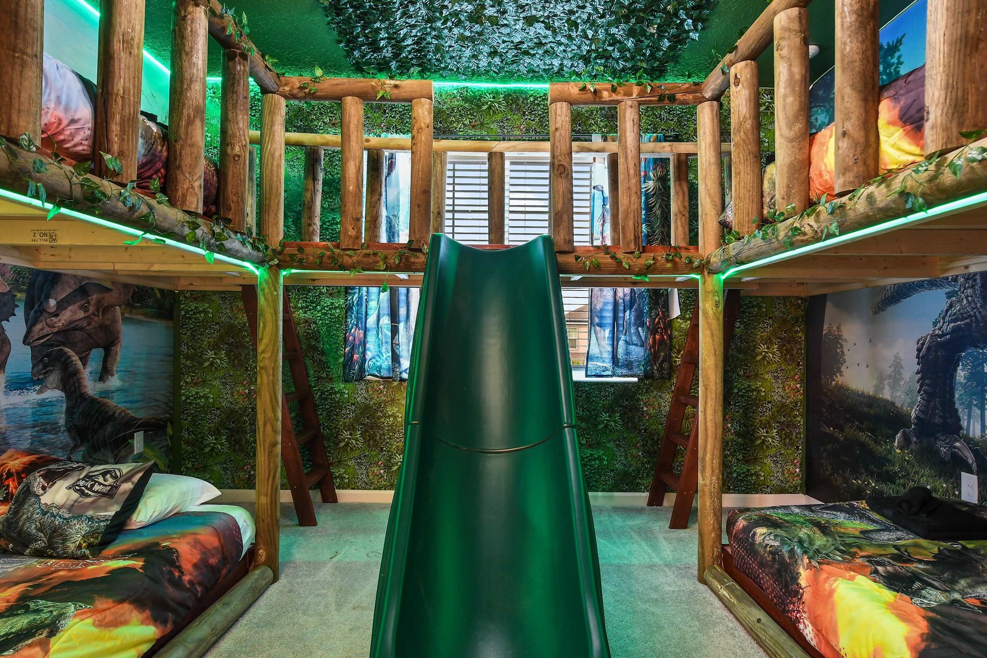 Dinosaur-themed bunk room with slide, jungle decor, and glowing green lights.