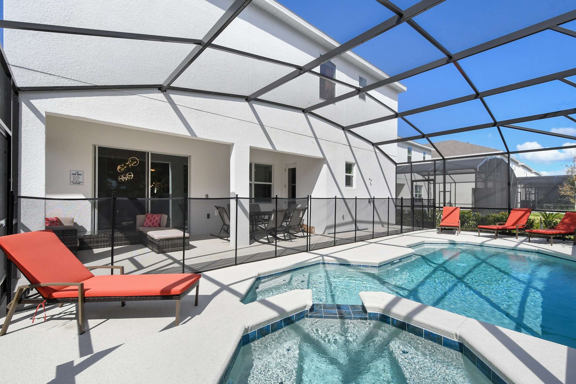 Screened-in pool with spa overlooking a serene lake and lush greenery.