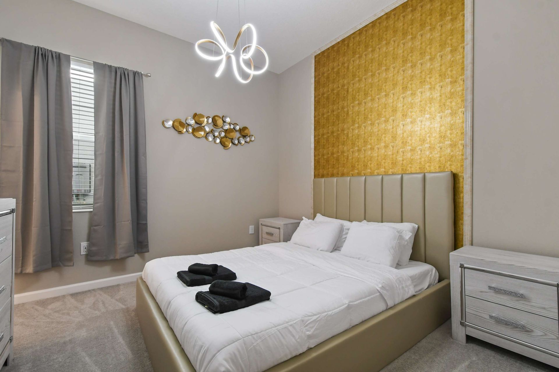 Sophisticated bedroom with gold accent wall, modern lighting, and cozy bedding.