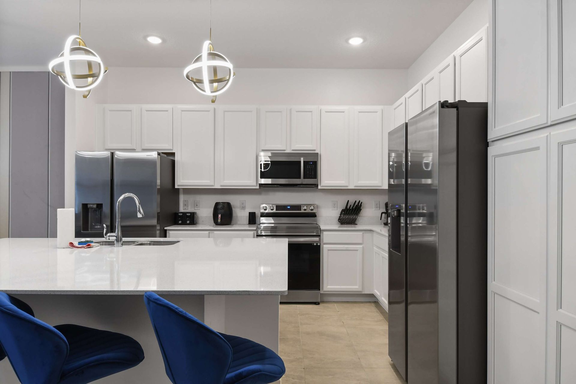 Modern kitchen with stainless steel appliances, sleek lighting, and island seating.
