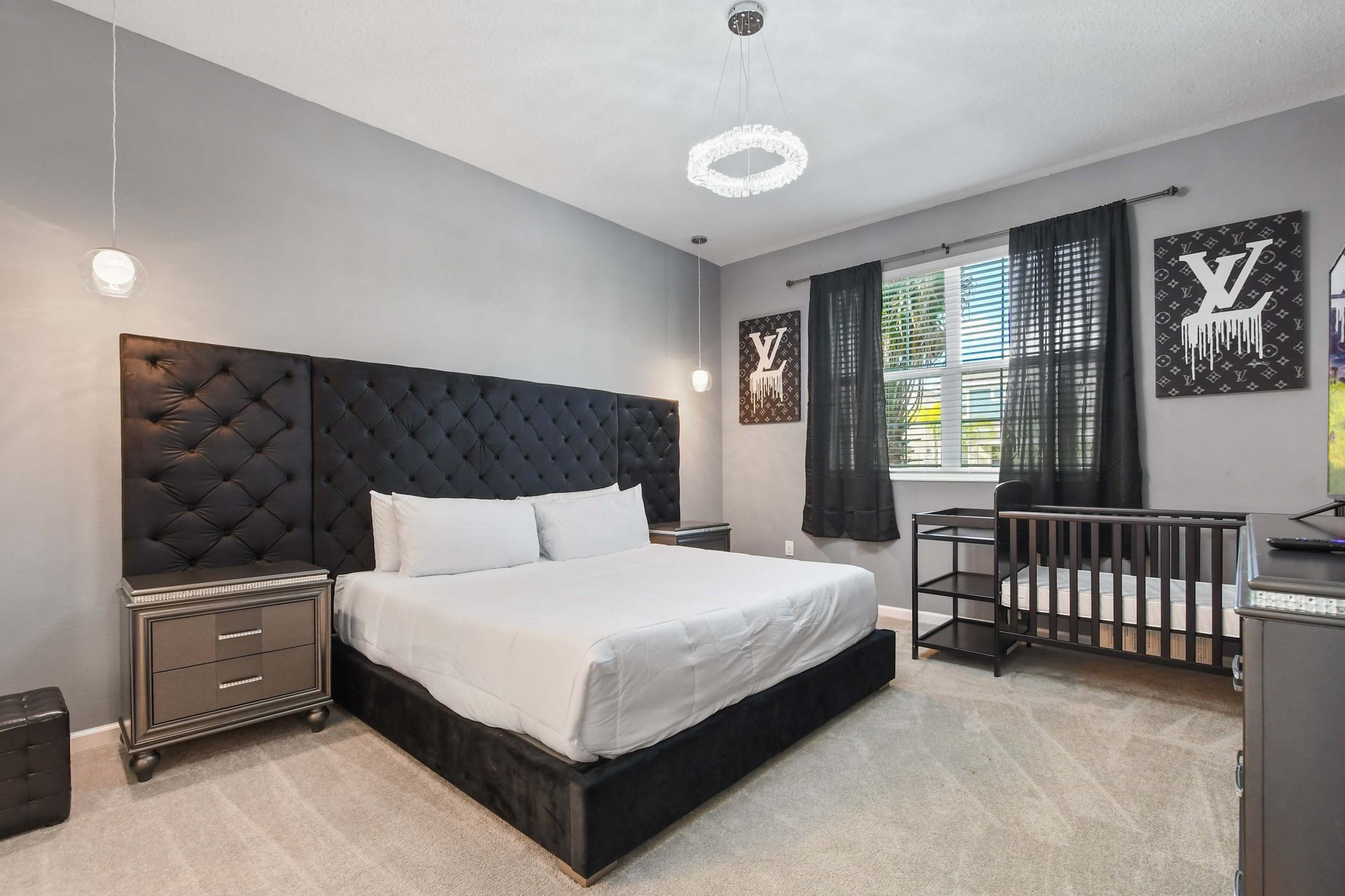 Chic master bedroom with tufted headboard, modern decor, and a convenient crib.