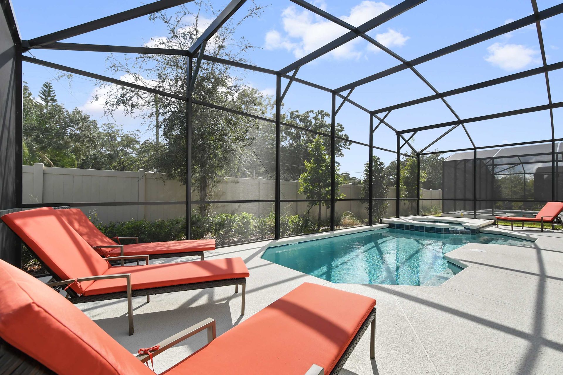 Screened-in pool with spa overlooking a serene lake and lush greenery.