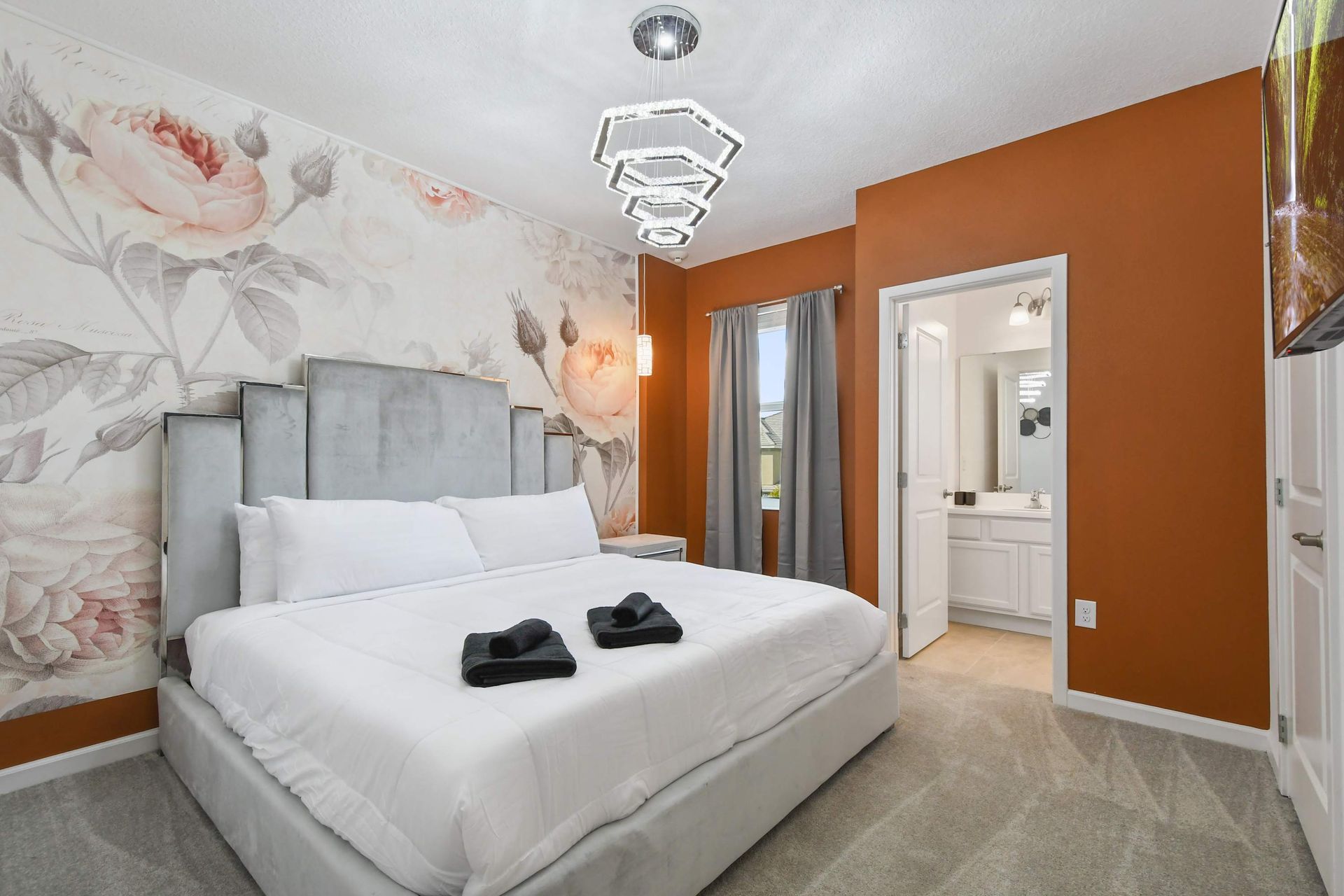 Floral-themed bedroom with velvet bed, warm tones, and en-suite bathroom.
