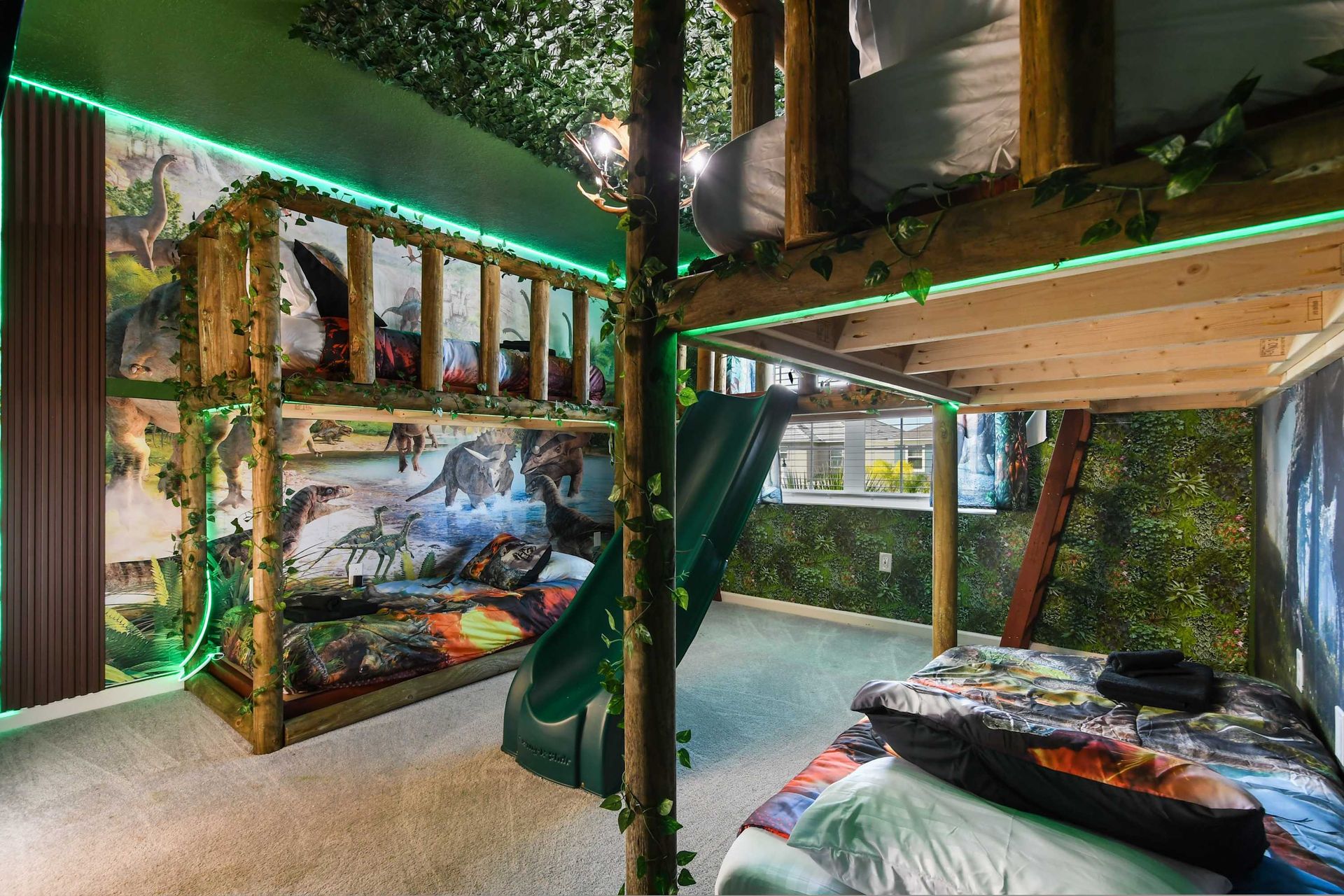 Dinosaur-themed bunk room with slide, vibrant lighting, and jungle decor.