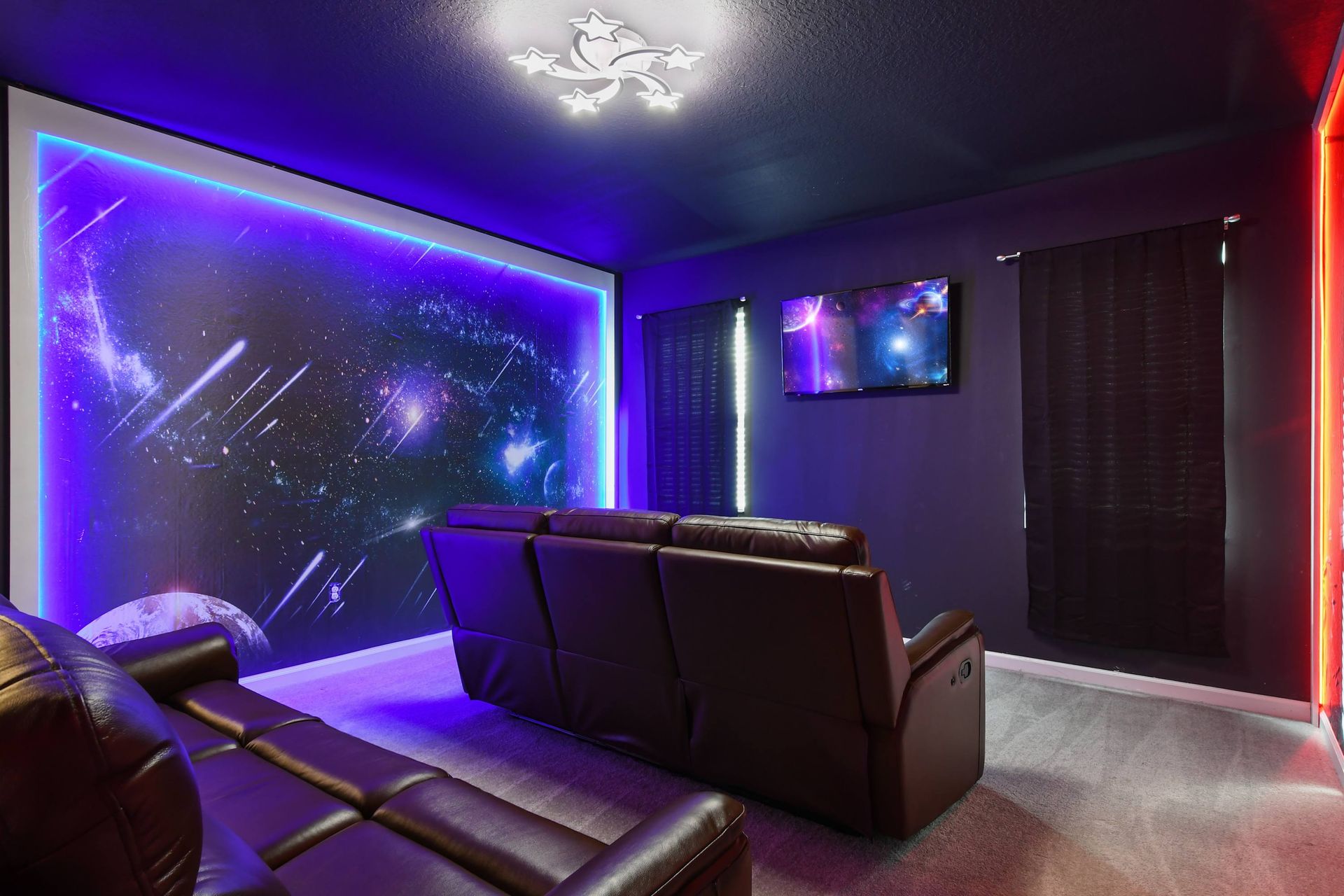 Galaxy-themed home theater with reclining seats, neon lighting, and starry walls.