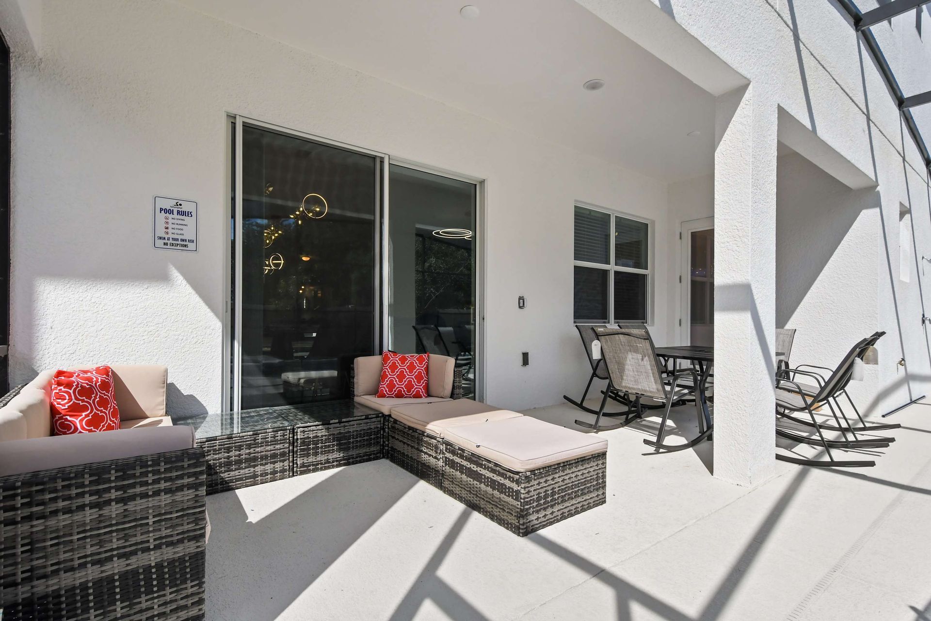 Relax on the covered patio with cozy seating and a dining area by the pool.